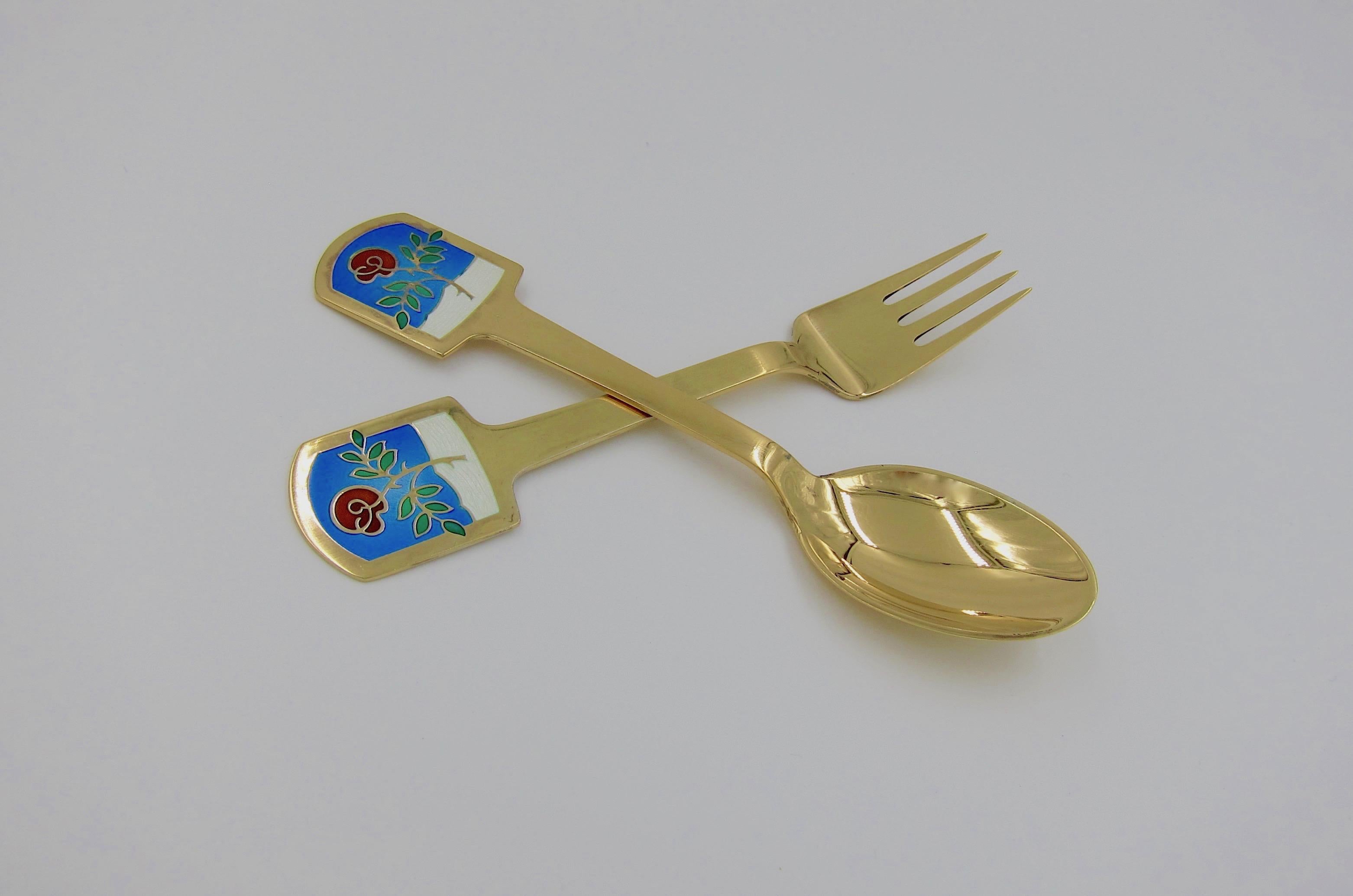 A Danish gilt sterling silver and enamel Christmas fork and spoon set from Anton Michelsen of Copenhagen, Denmark. Poul Hanmann (1915-1981) created this 