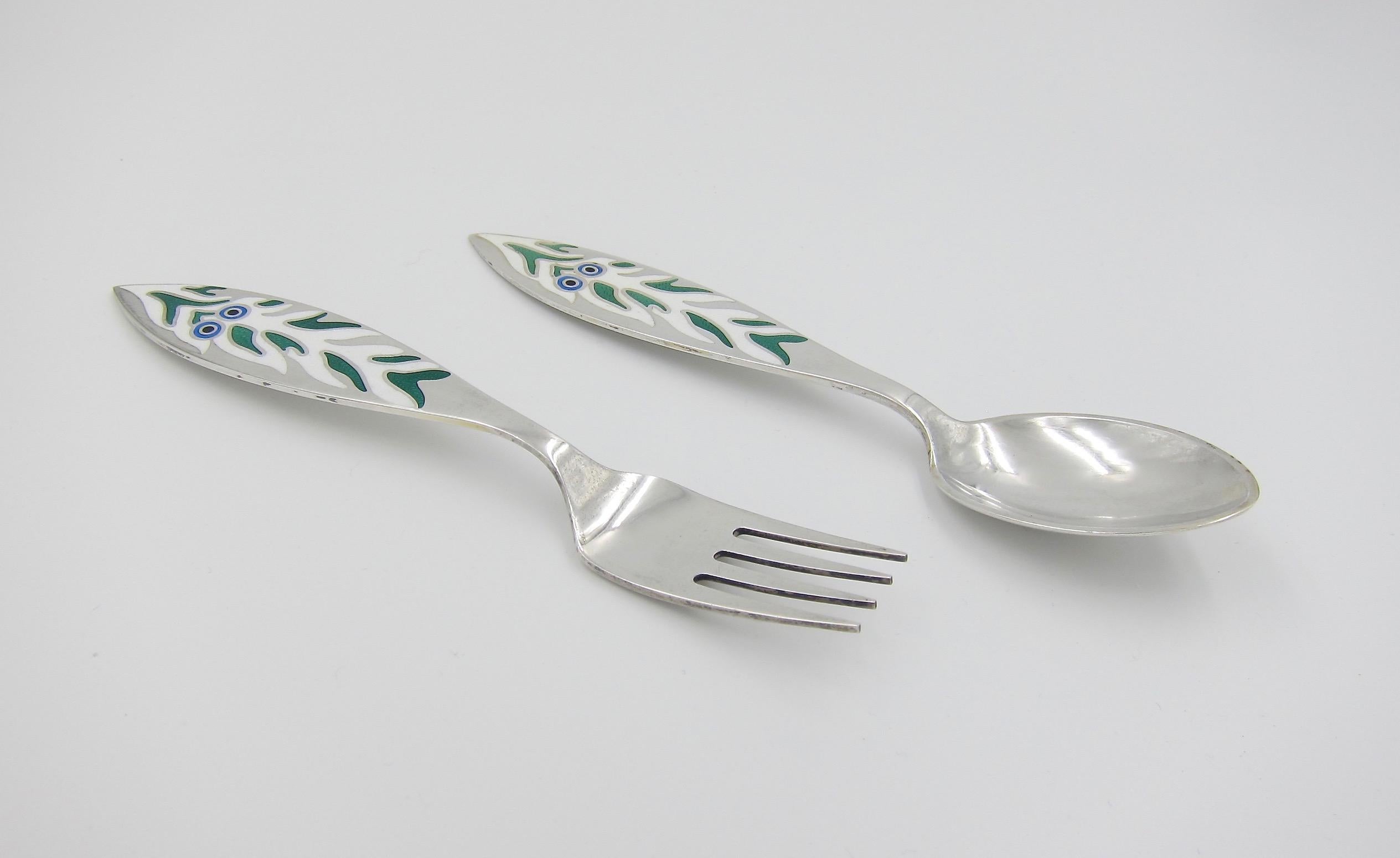 A Danish sterling silver and enamel Christmas fork and spoon set from Anton Michelsen of Copenhagen, Denmark. Artist Mogens Zieler (1905-1983) created the 