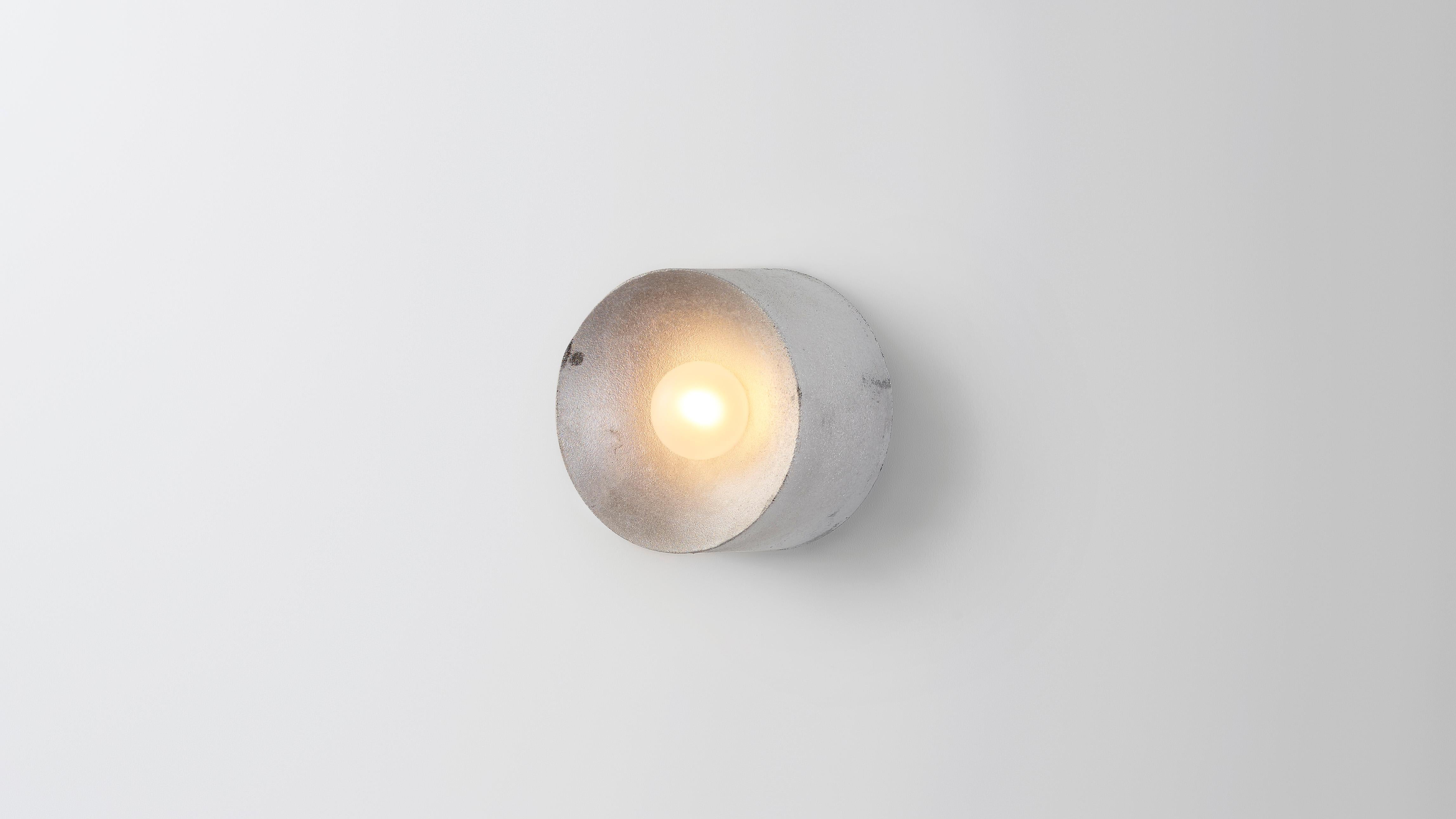 Anton mini in aluminum by Volker Haug 
Anton series
Dimensions: Ø 13 x D 8 cm.
Materials: Cast aluminum
Finish: Raw
Lamp: G9 LED (240V / 120V US). 12V option available.
Glass bulb: 4.5 cm ø, Frosted
Weight: 1kg.

Anton mini (Ø13 cm) is cast as raw