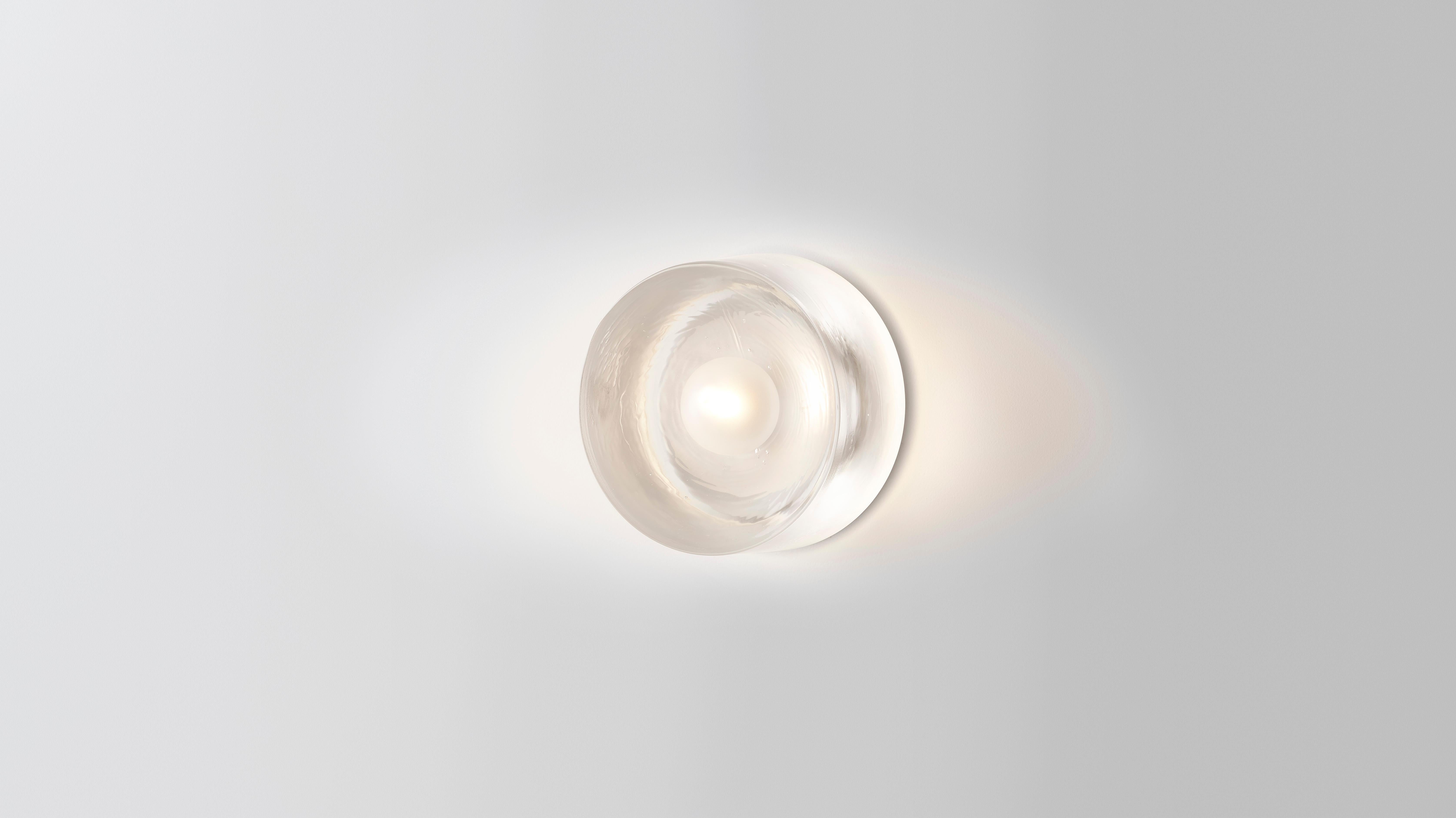 Anton mini in glass by Volker Haug 
Anton series
Dimensions: Ø 13 x D 8 cm.
Materials: Cast glass
Backing plate: Polished
Lamp: G9 LED (240V / 120V US). 12V option available
Glass bulb: 4.5 cm ø, Frosted
Weight: 2kg.

The Glass Anton has a diameter