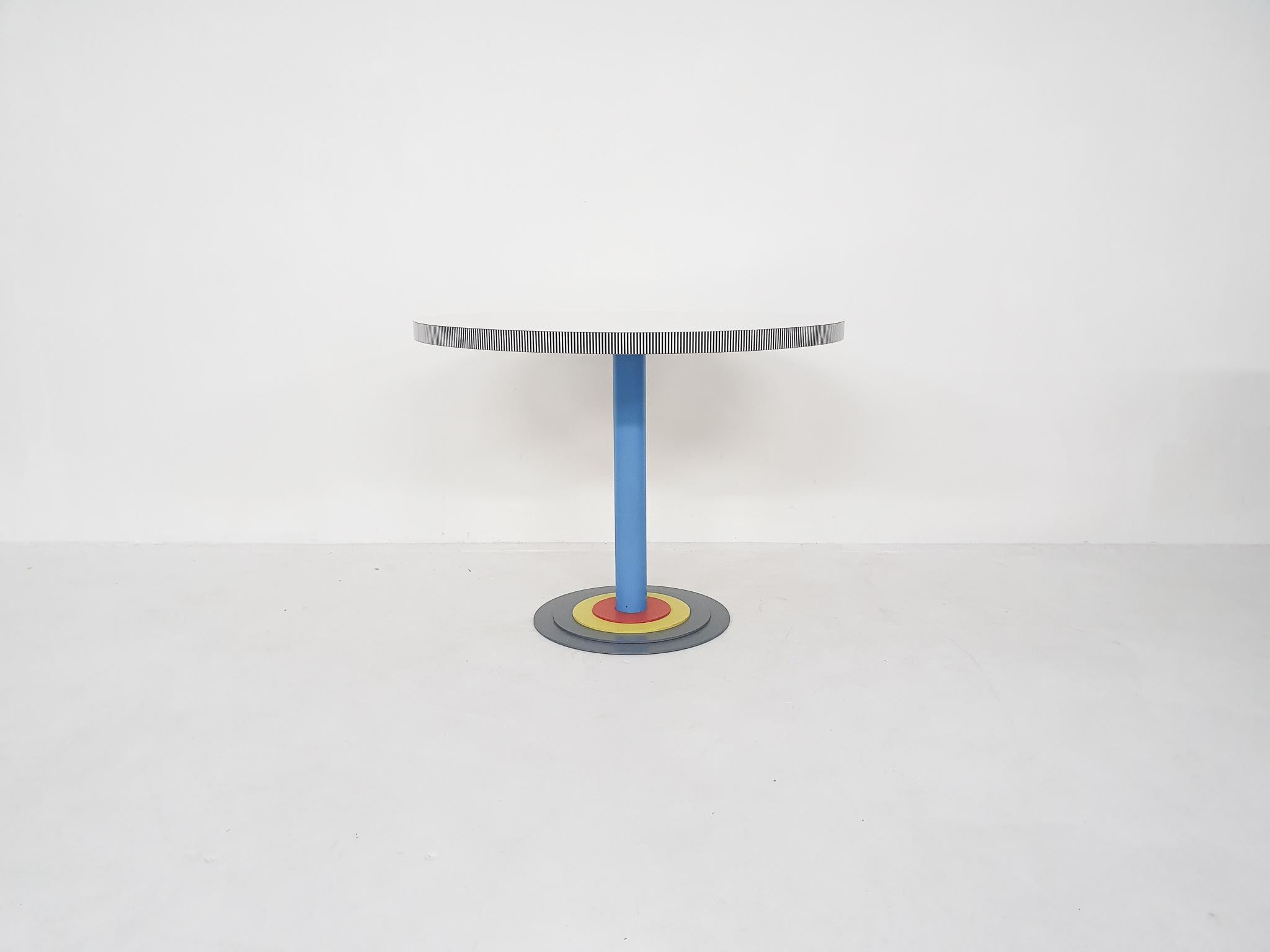 Round Formica dining table on heavy metal pedestal foot. The design was inspired by the Memphis Milano movement with its shape and colors.
Some scratches in the Formica top.