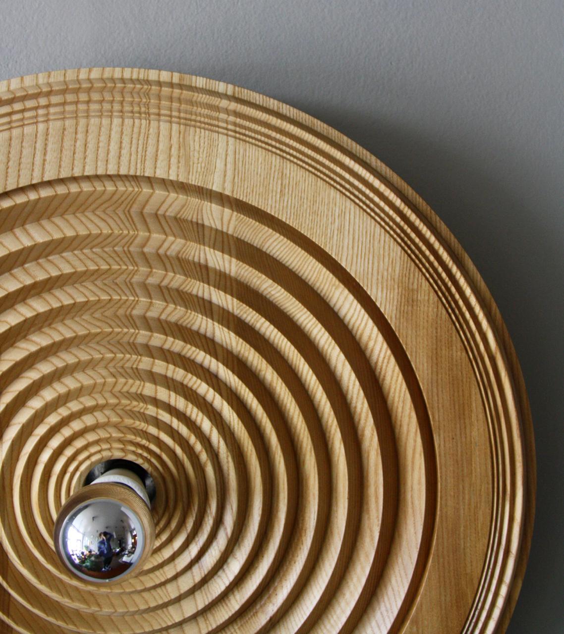 A vintage Czech wall light in oak designed and made by Antonín Hepnar, circa 1980. The lamp is made of solid wood which has been turned to create asymmetrically spaced concentric rings -similar to how rings emanate from a stone dropped into water.