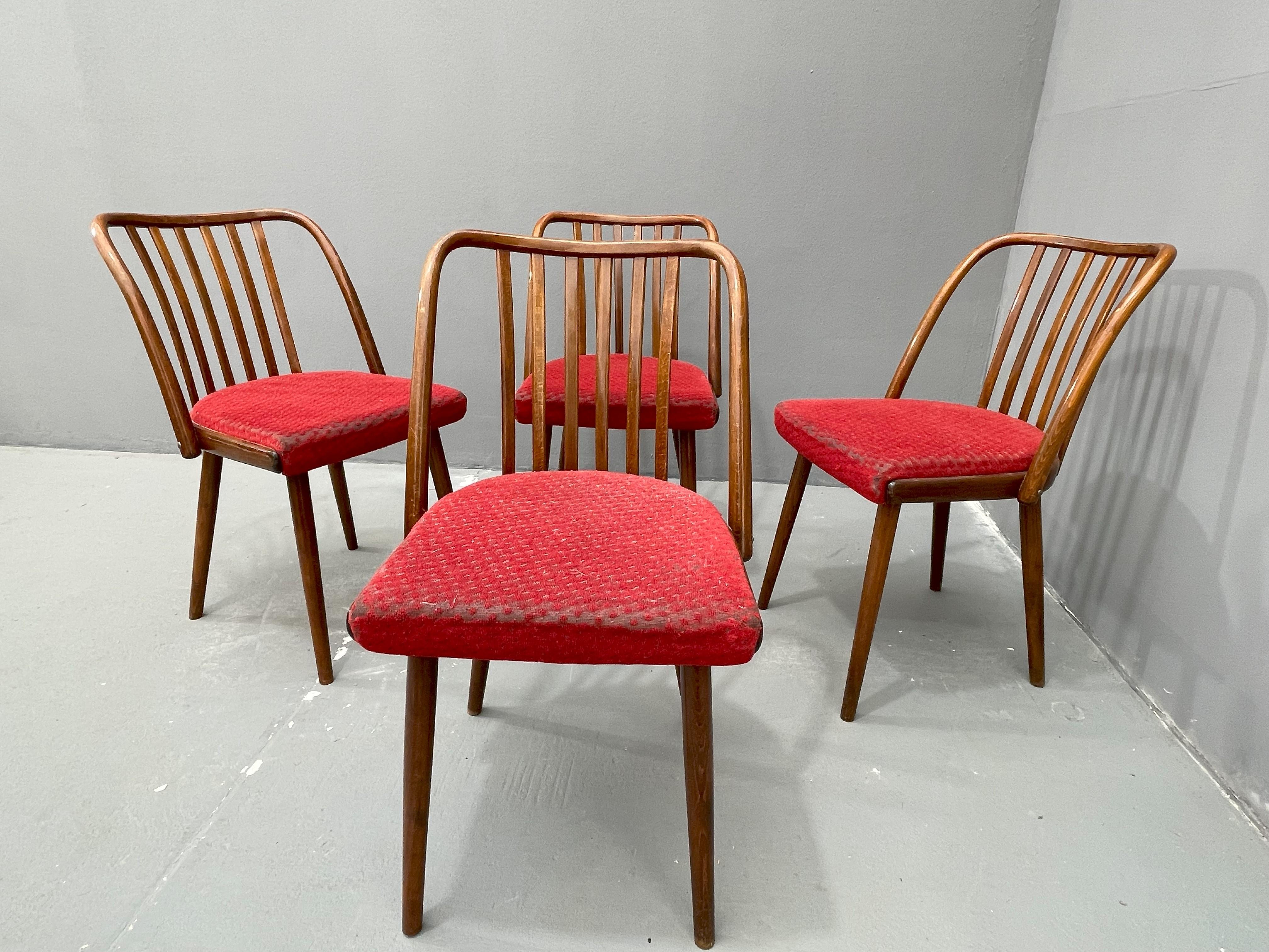 A set of four wooden chairs designed by Antonín Šuman for TON company. Manufactured in the former Czechoslovakia in the 1960s. The chairs feature a characteristic bentwood frame with a slatted backrest and upholstered seat in red fabric. Condition