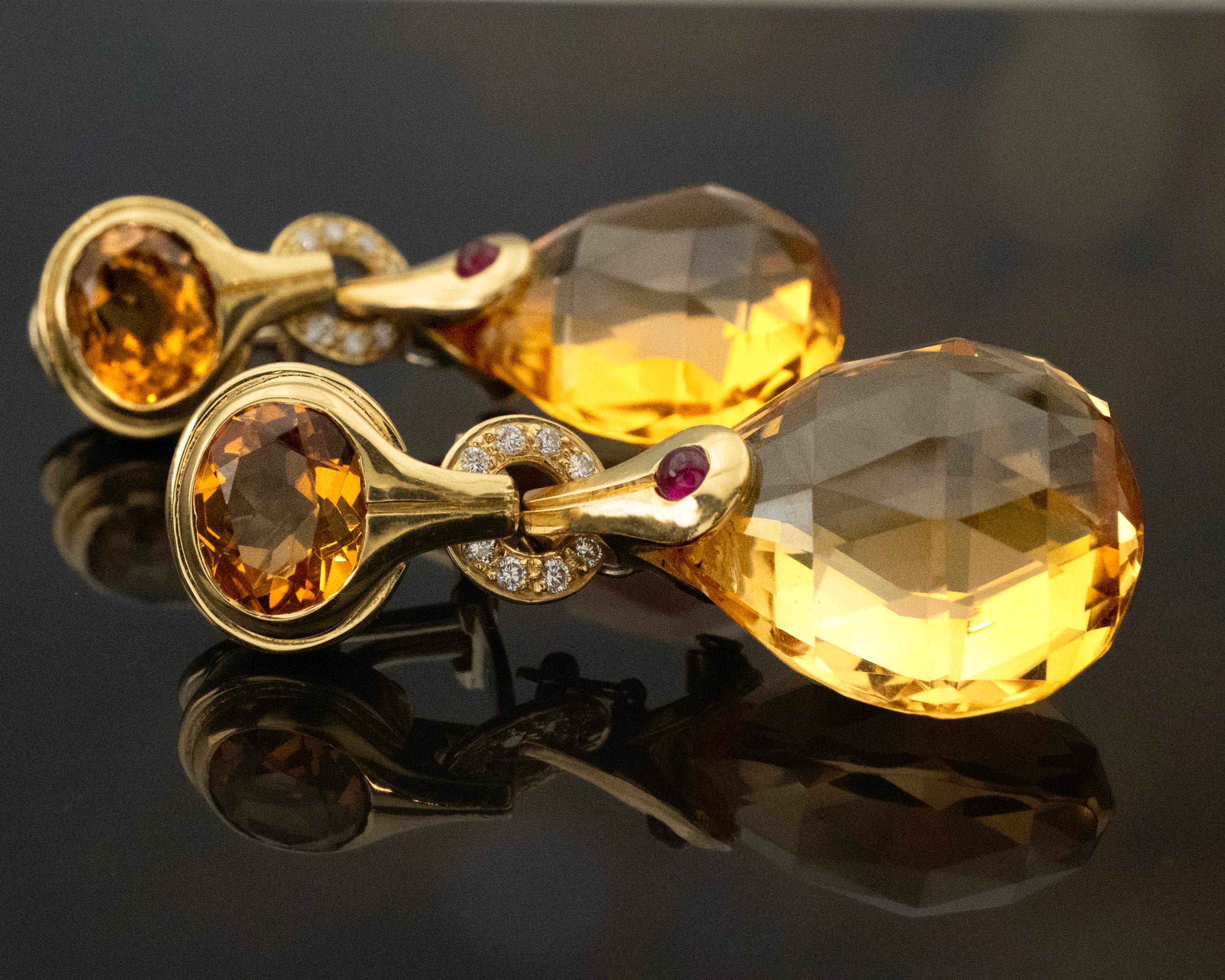 These Antonini Milano earrings from the Madeira Collection are crafted in 18k yellow gold and measure 4.5 cm long. They feature two faceted pear-shaped Madeira citrines, each suspended from a round citrine set in a gold bezel. The citrines have a