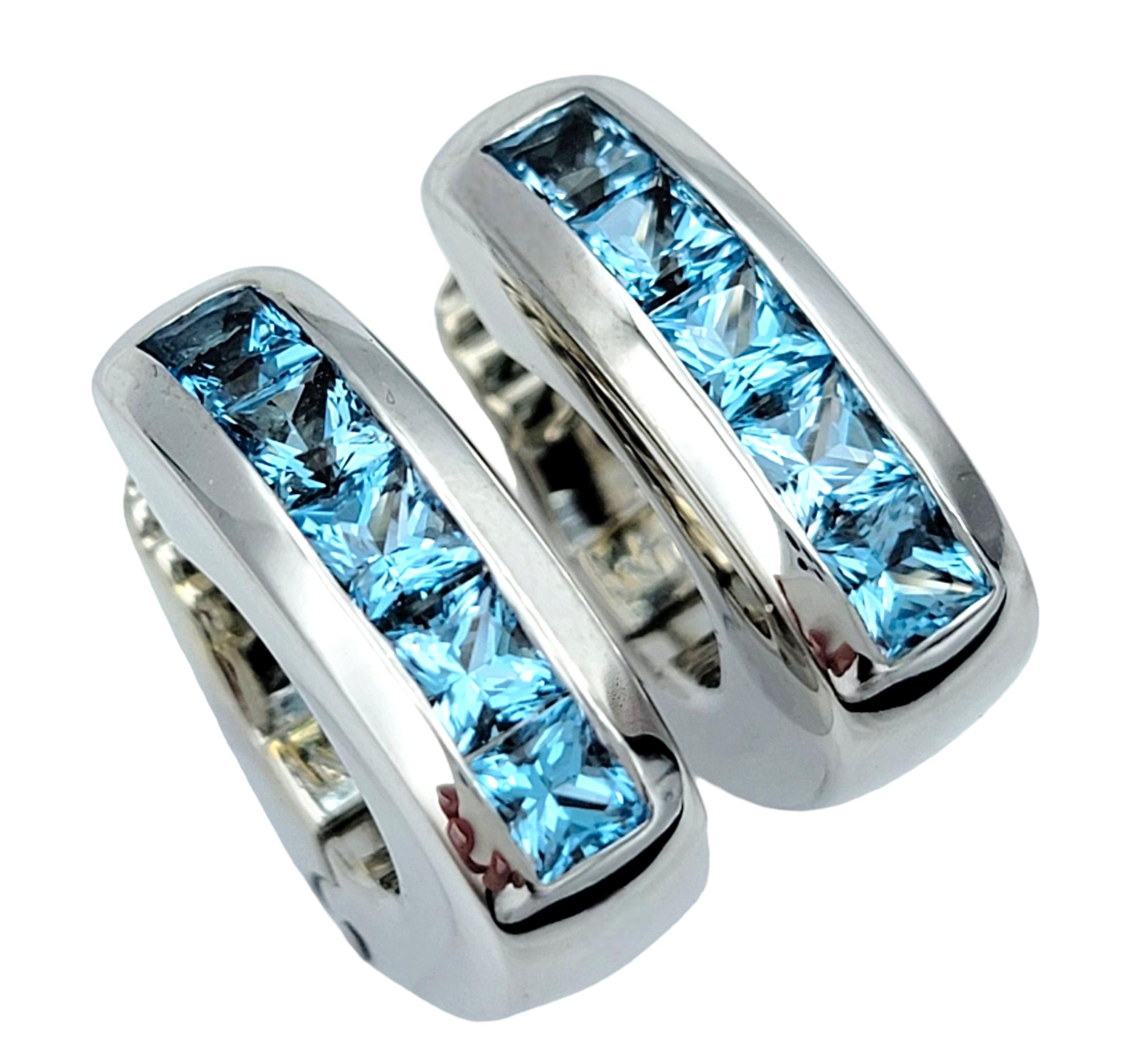 Crafted by Antonini, these stunning huggie hoop earrings feature a contemporary design that effortlessly blends elegance with modernity. Set in luxurious 18 karat white gold, the earrings showcase a channel-set arrangement of vibrant blue topaz