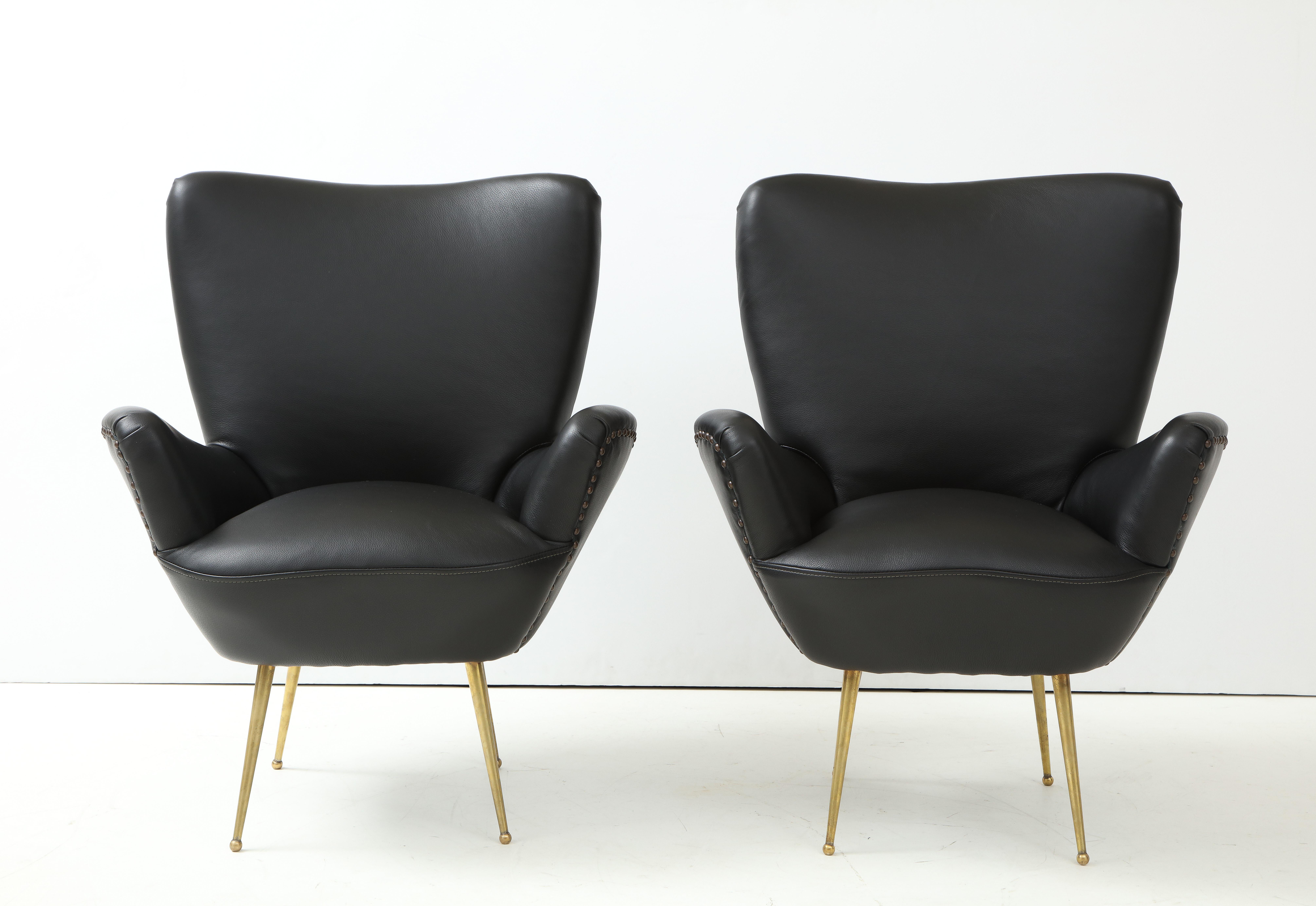 Stunning pair of 1960's modernist sculptural lounge chairs designed by Antonino Gorgone, with solid brass legs fully restored and reupholstered in leather with bronze nails detail.