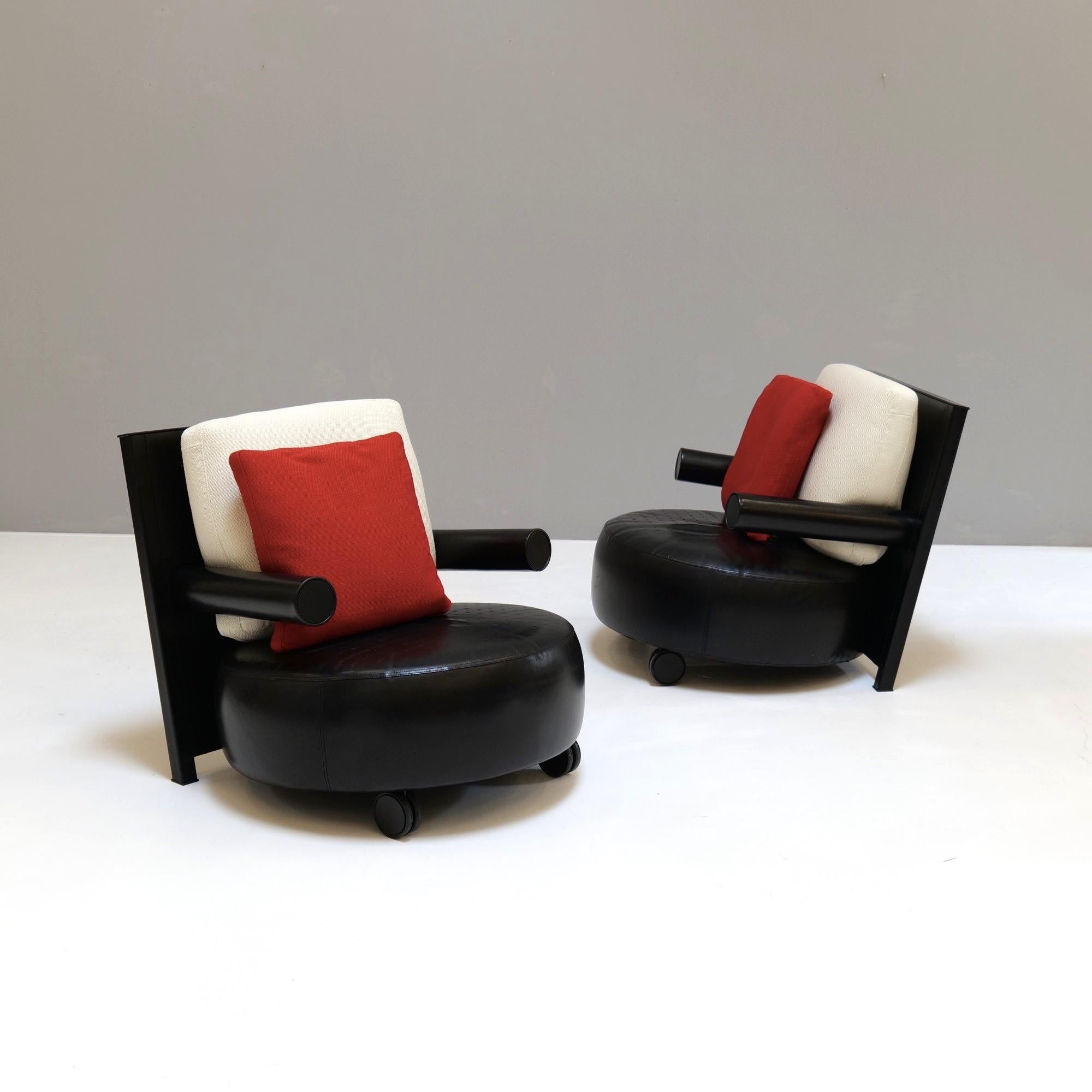 Une paire de fauteuils en cuir noir d'Antonio Citterio pour B&B Italia, un classique du design post-moderne.

Le jeu géométrique des tubes, du disque épais, du carré et des roulettes confère au fauteuil une légèreté ludique.

Deux coussins de
