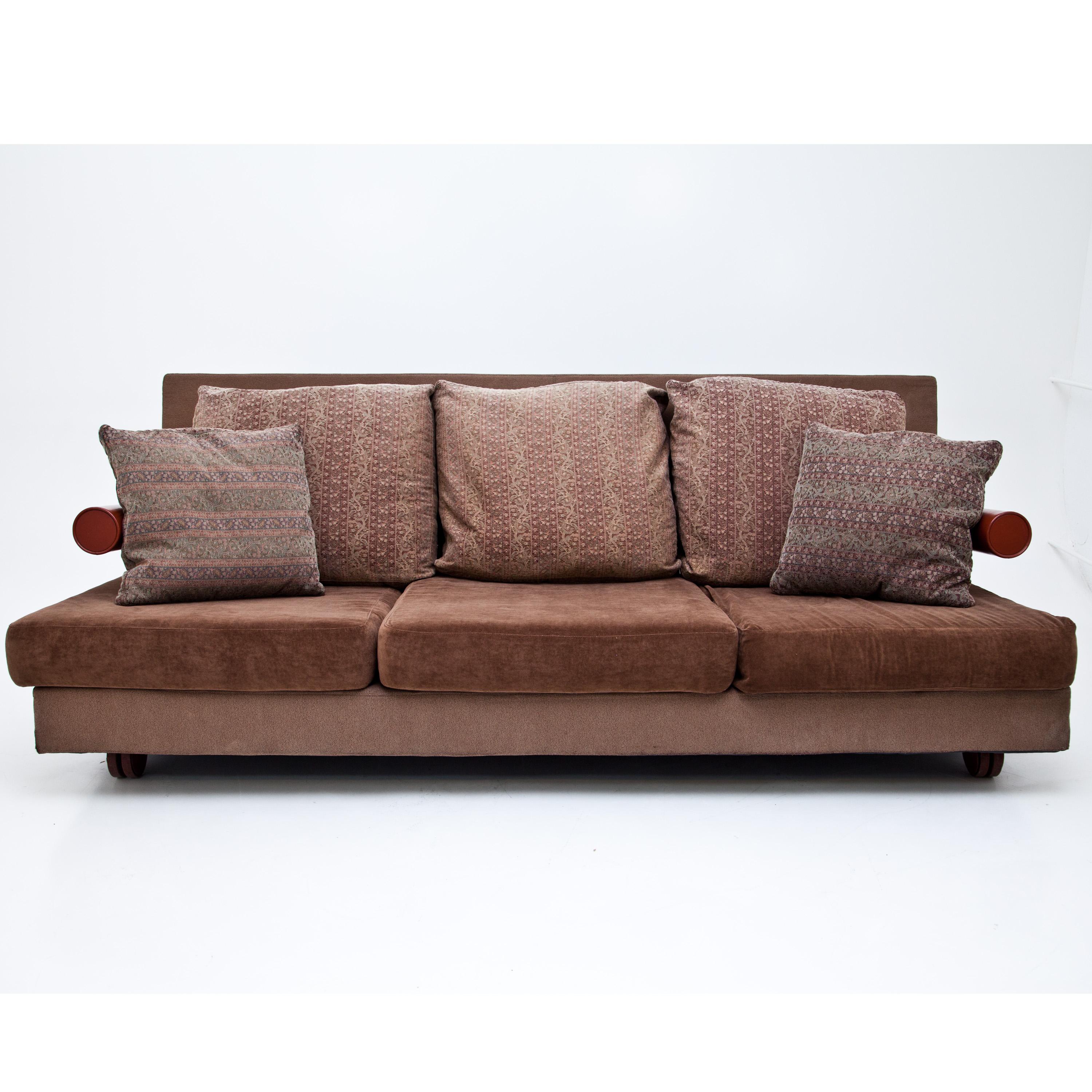 Brown three-seat sofa on castors with rectangular seat and backrest. The brick-red cylindrical armrests are made of metal. The Sity sofa was designed by Antonio Citterio for B&B Italia in 1986 and was awarded the Italian Industrial Prize, the