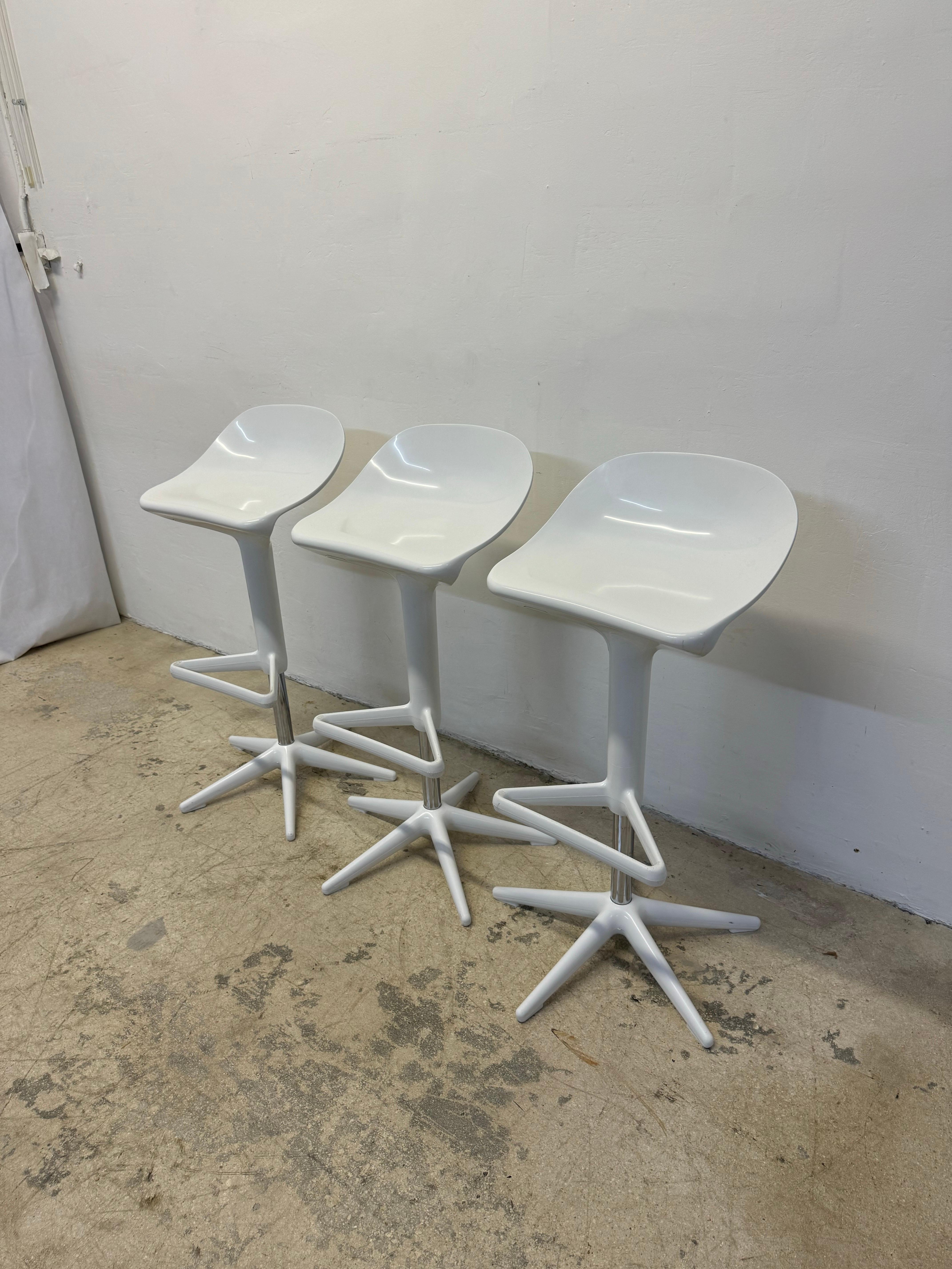 Set of three white adjustable Spoon stools designed by Antonio Citterio for Kartell.   The alll white stools have a sophisticated gas lift pump which adjusts the seat height with the handle being concealed inside the seat design.  These curved seat