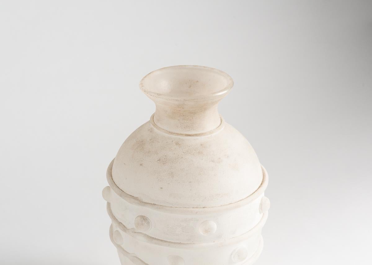 Made in 1983 by Antonio da Ros for Vetreria Gino Cenedese, this near-opaque, white vase possesses an elegant simplicity of form, and features, around its widest point, an abstract, geometric relief. It was made with the rare scavo technique, by