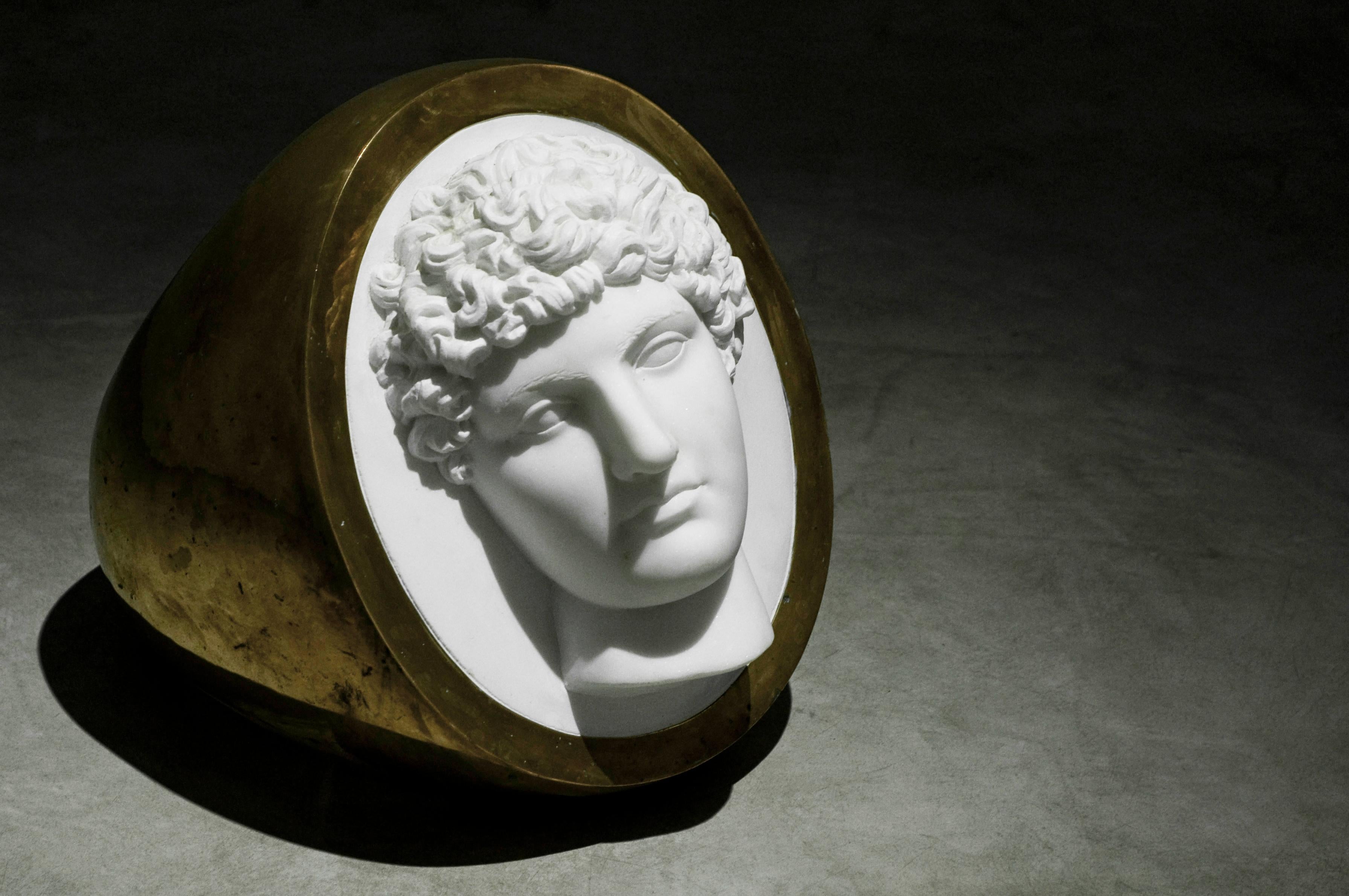 Cette bague-sculpture est en bronze et en marbre, à partir de l'auriculaire masculin, modèle Chevalier, généralement avec des sceaux, des figures nobles et des armoiries de la famille, en hommage aux ancêtres, ce qui renvoie ici à la grandeur de la