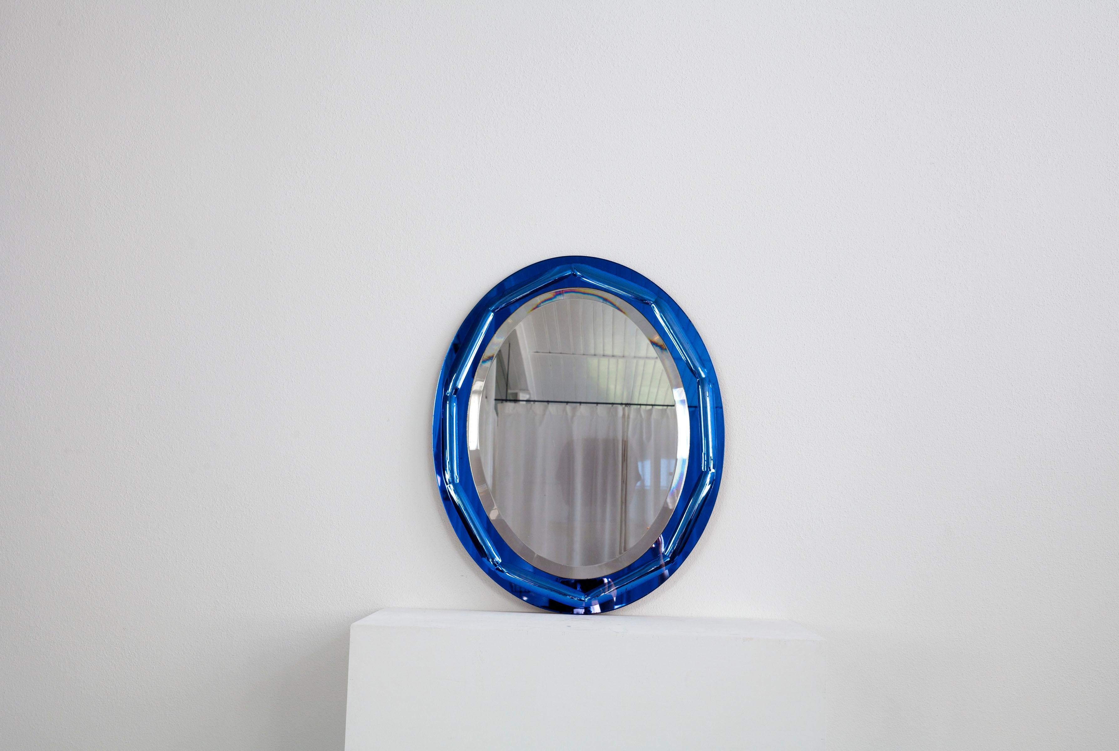 This oval, Italian wall mirror dates from the 60s. The special feature of this mirror is the frame, which is also made of reflective glass, and there is also a pattern in the frame itself. The glass of the frame is coloured and takes on an intense