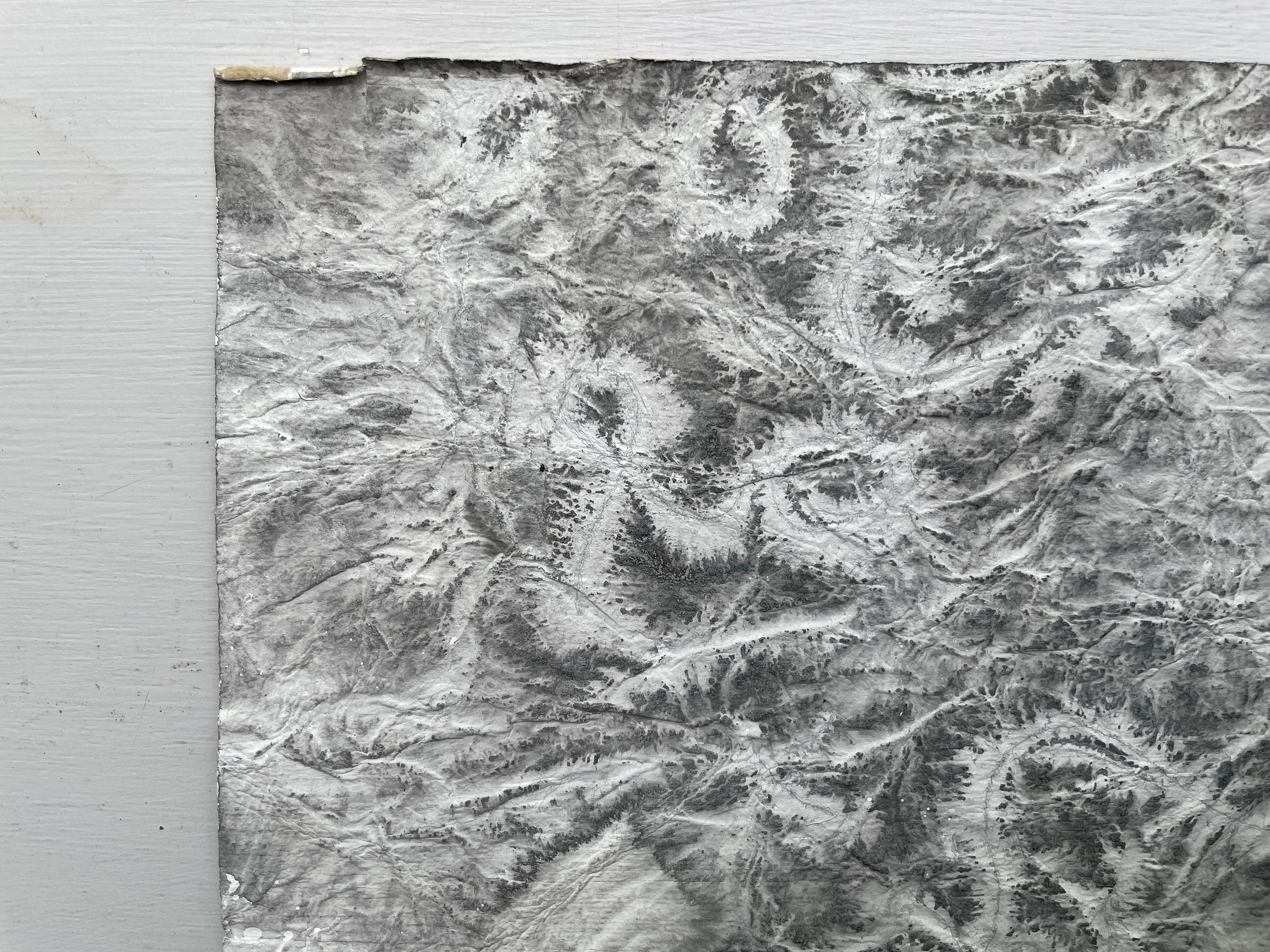 This is a sumi ink, acrylic, and mixed media painting on paper in gray, black, and white with a central white medallion. It is a highly textured work on heavy, handmade khadi paper from India, hand torn for irregular edges. This painting can be