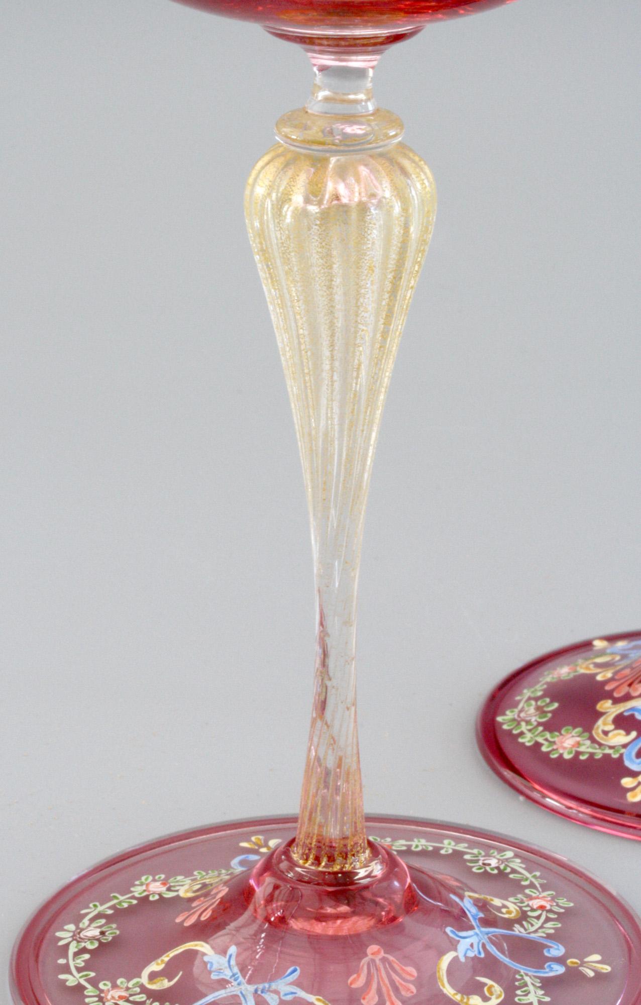 A very fine and rare pair Antonio Salviati Venetian Revival enameled wine glasses dating from circa 1900. This stylish pair of glasses stand on a rounded doomed pink coloured glass foot with folded rims on a hollow blown glass ribbed and shaped stem