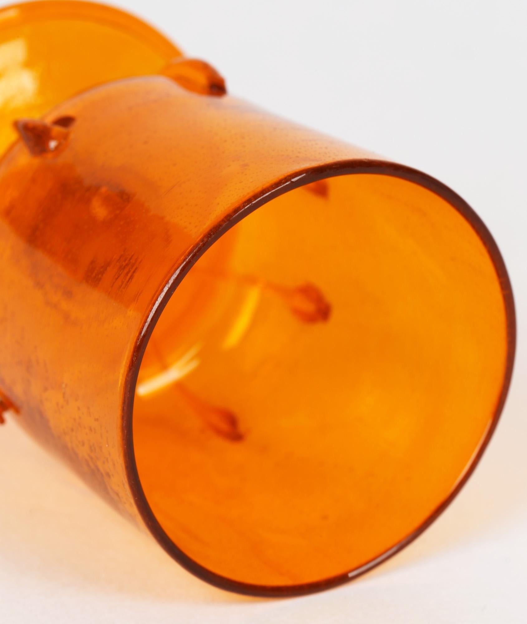 A stylish Venetian revival orange wine glass made by Salviati around 1900. The small cylindrical bodied glass stands on a slightly domed rounded foot with folded rim and short stem with trailed applications around the lower body of the glass. The