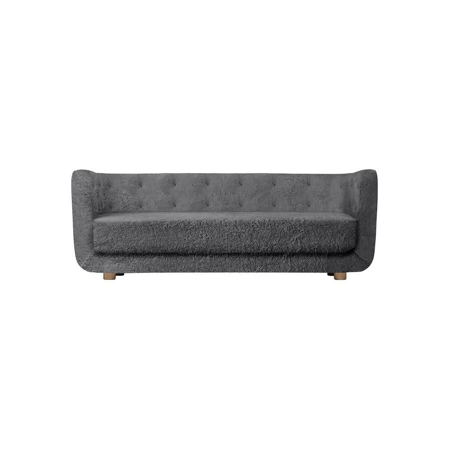 Antrachite sheepskin and smoked oak Vilhelm sofa by Lassen.
Dimensions: W 217 x D 88 x H 80 cm 
Materials: sheepskin, oak.

Vilhelm is a beautiful padded three-seater sofa designed by Flemming Lassen in 1935. A sofa must be able to function in