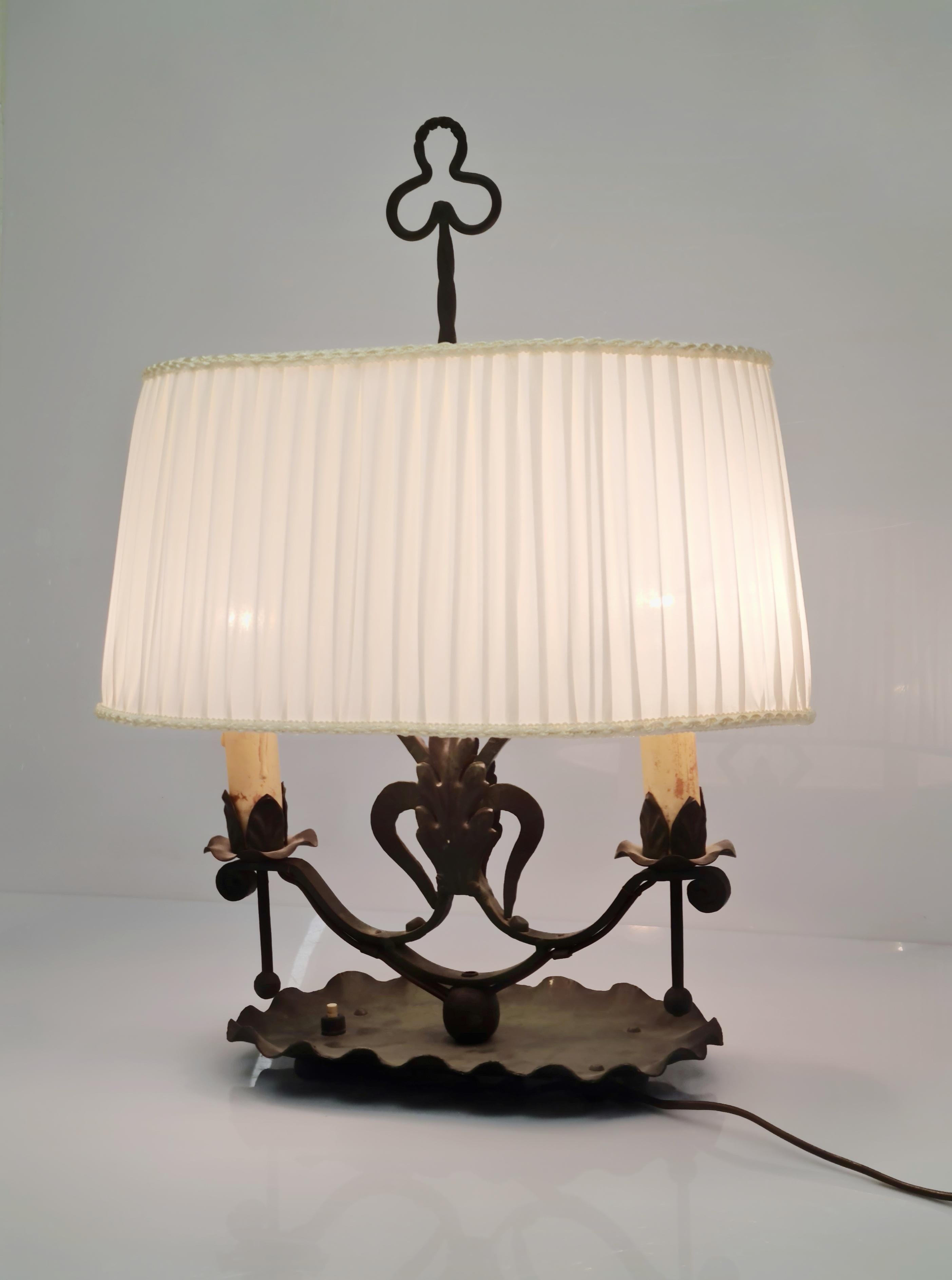 A beautiful table lamp made from wrought iron, designed by Antti Hakkaraien, and manufactured by his company Taidetakomo A. Hakkarainen in the 1930s.
The table lamp is in great condition with a browinsh/greenish patina. The lamp shade has been of