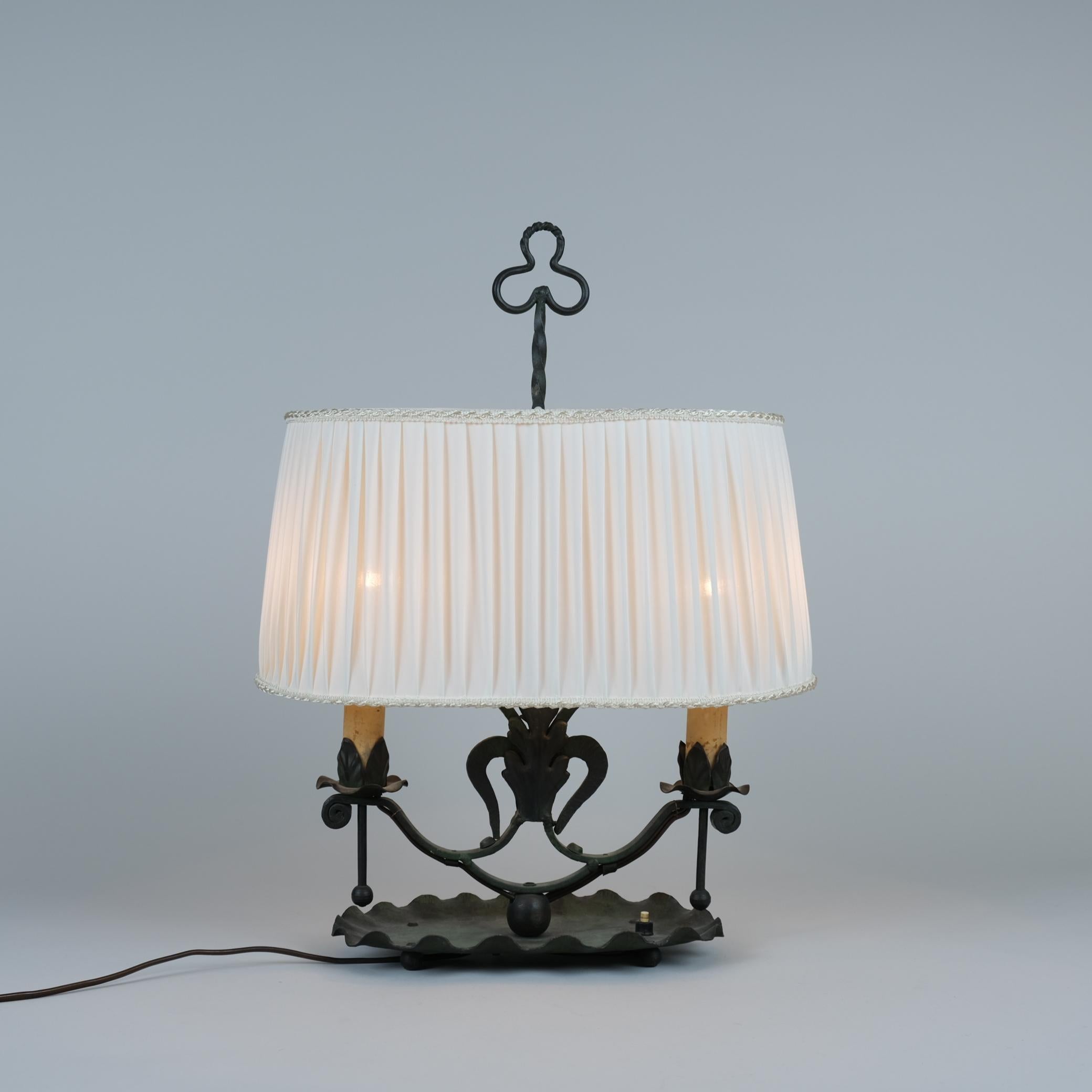 A beautiful table lamp made from wrought iron, designed by Antti Hakkaraien, and manufactured by his company Taidetakomo A. Hakkarainen in the 1930s.
The table lamp is in great condition with a browinsh/greenish patina. The lamp shade has been of