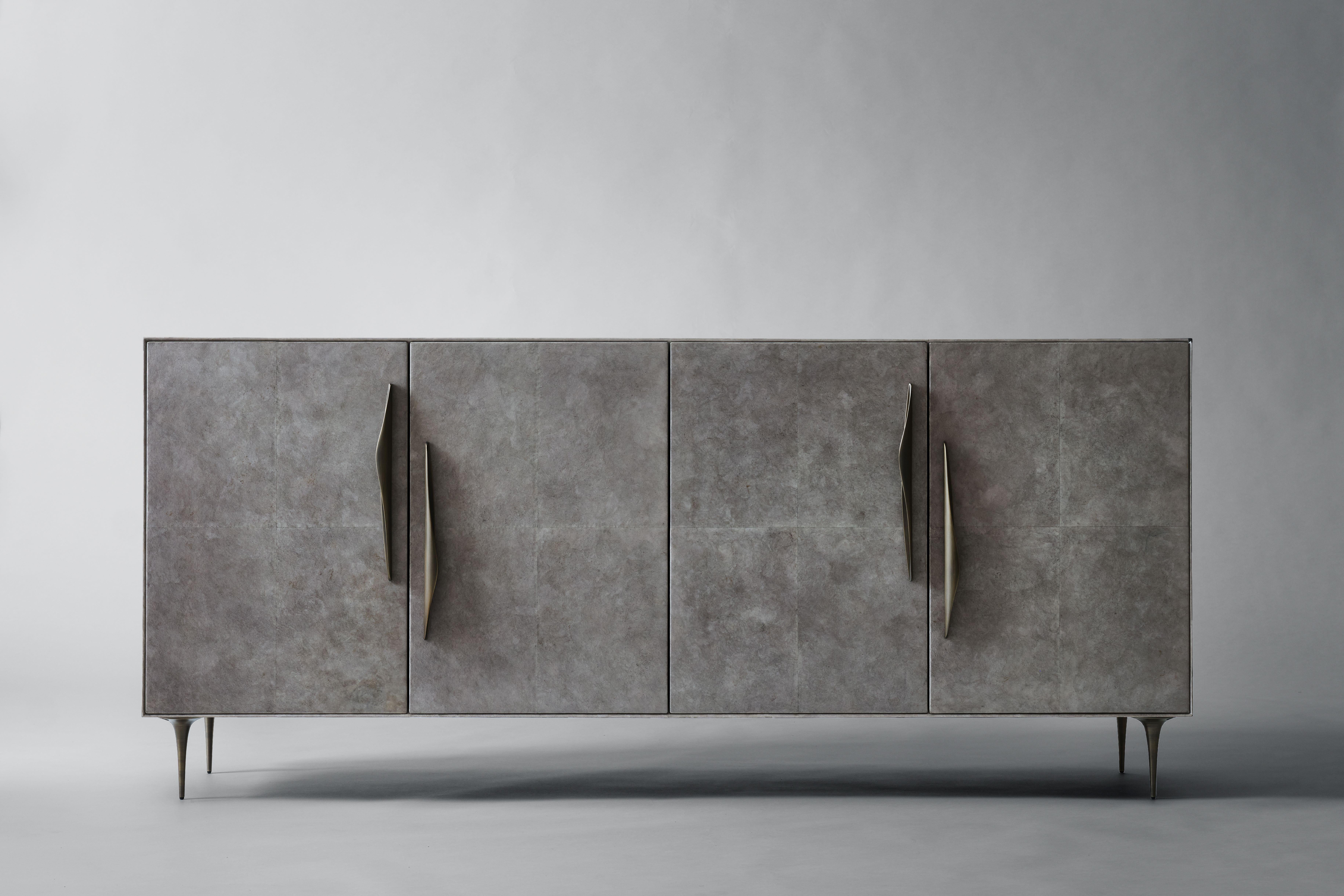 Inspired by vintage hardware found in Belgium, hand-cast bronze pulls in organic forms accent the Antwerp Cabinet. Clad in sheets of Carta, a characterful, plant-based alternative to parchment, the four-door piece stands on tapered bronze legs, with
