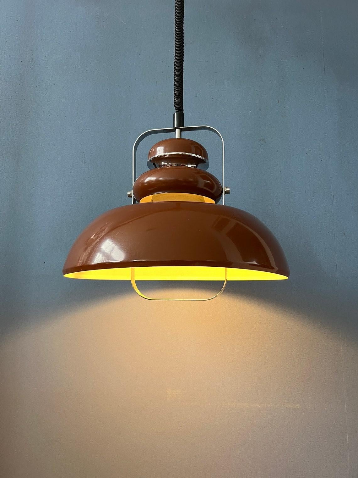 Vintage brown space age age pendant lamp by Anvia. The lamp is beautifully layered with brown parts and chrome parts. The height of the lamp can easily be adjusted with the rise/fall mechanism. The lamp requires one E27/26 (standard)