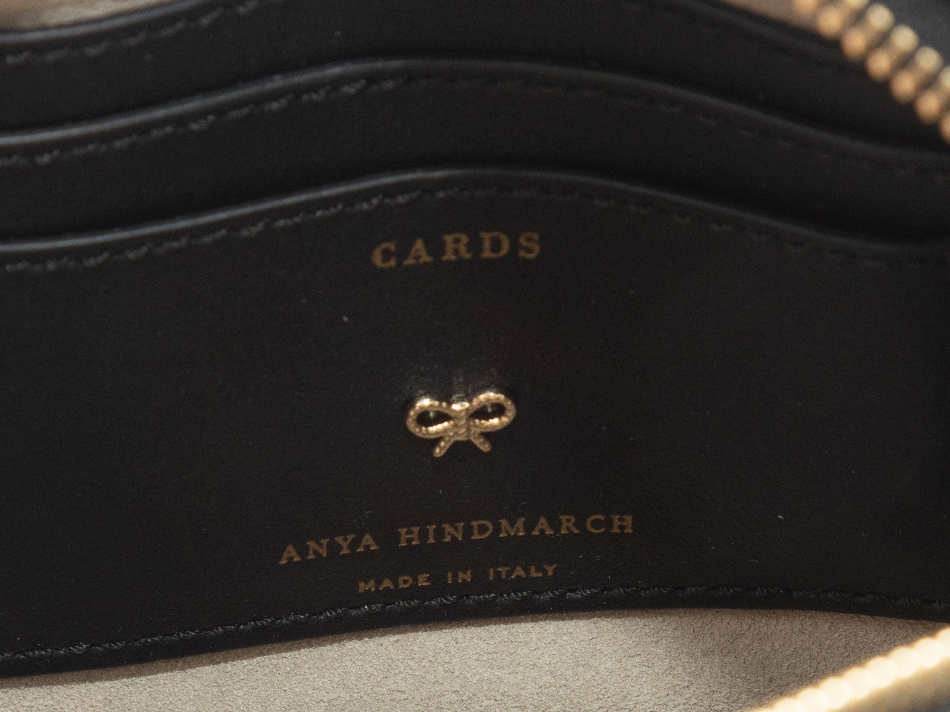 Product Details: Black & Multicolor Anya Hindmarch Allover Sticker Print Crossbody Bag. This bag features an embossed leather body, gold-tone hardware, interior card slots, a single flat crossbody strap, and a tassel-accented top zip closure. 7