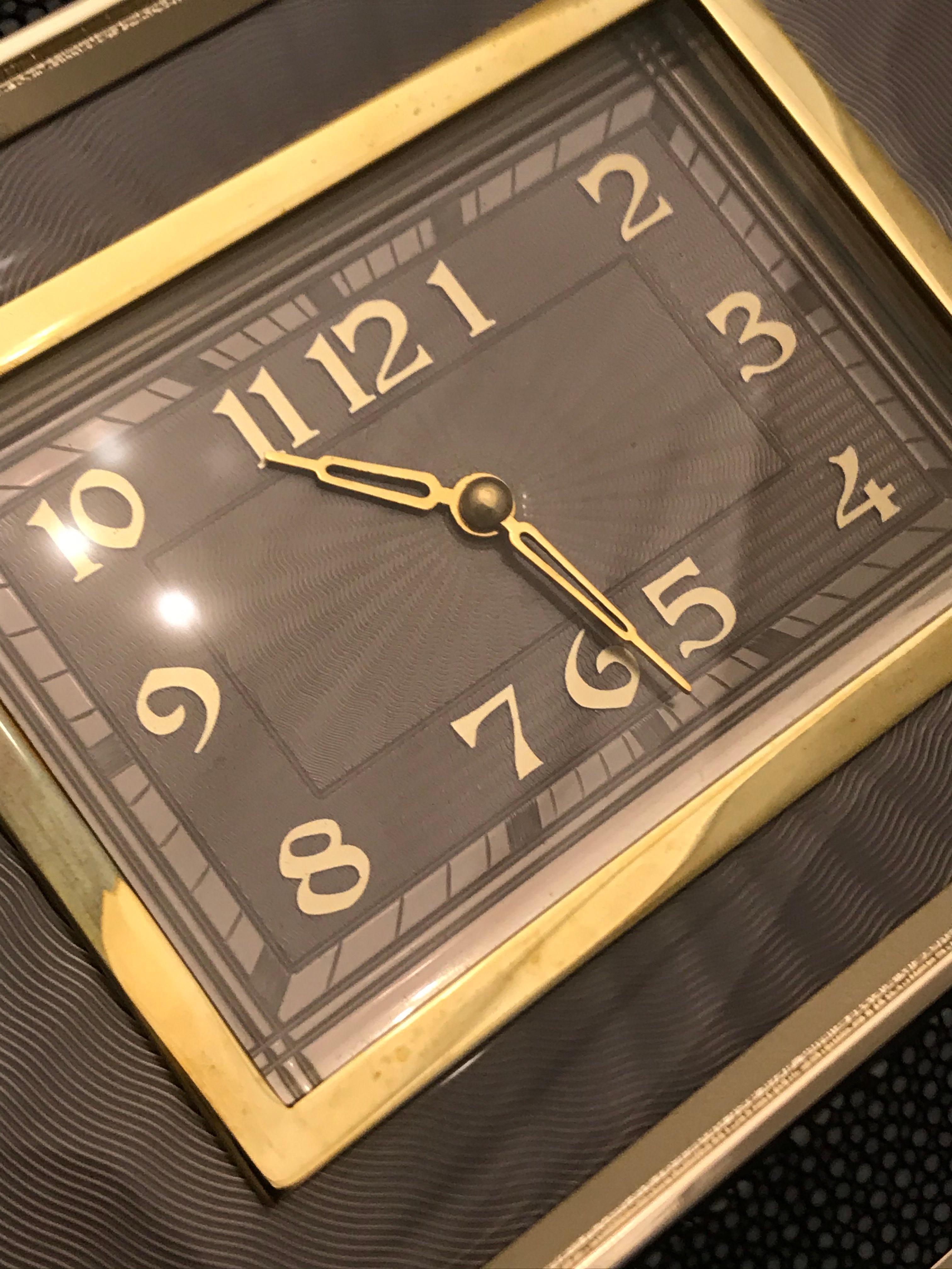 Rare pochette Anya Hindmarch Duke Clock de la marque éponyme. Sac de soirée de style boîte à cigarettes, principalement en galuchat, avec des bords inclinés et biseautés. Forme rectangulaire structurée avec émail guilloché dans les tons de cloches