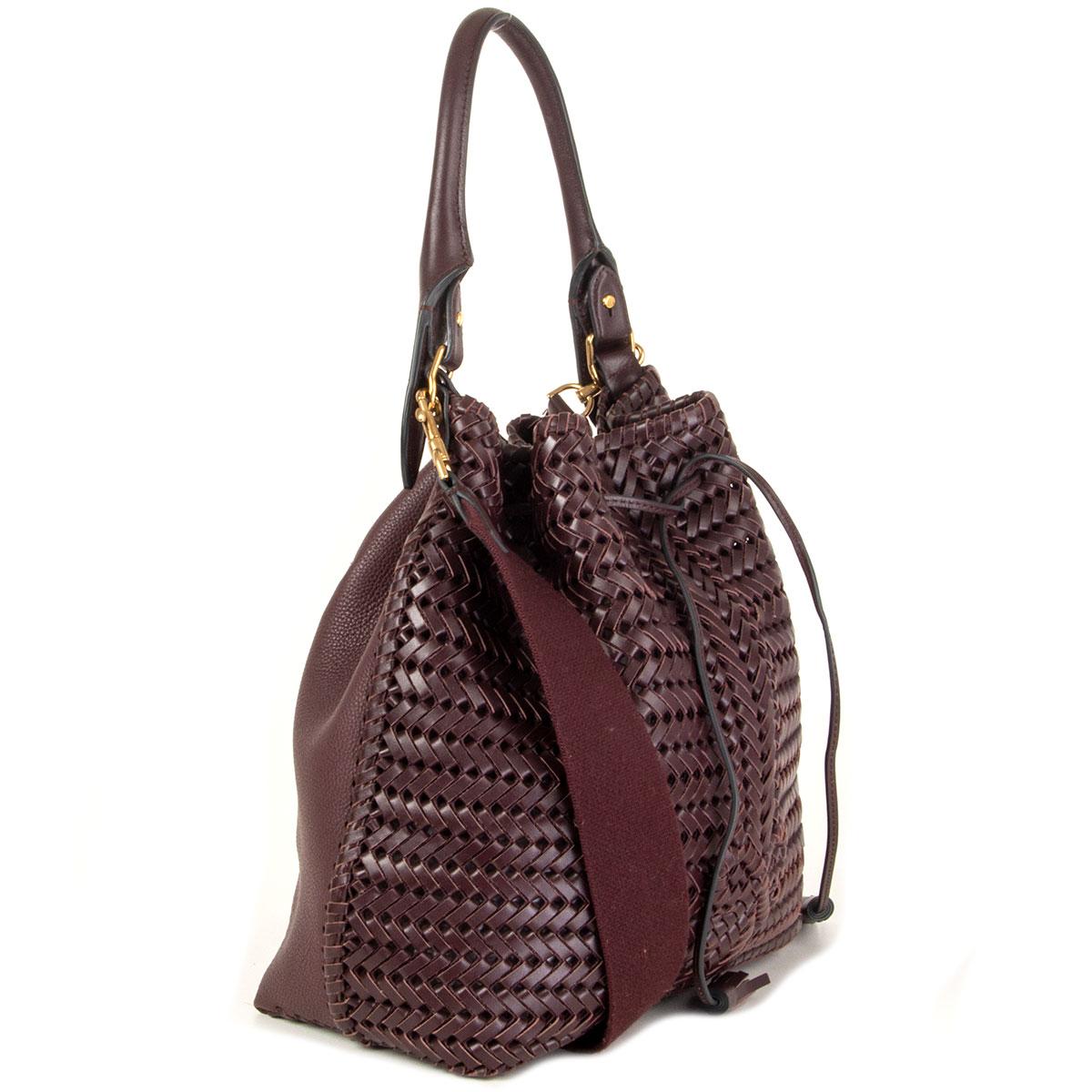 100% authentic Anya Hindmarch Neeson drawstring shoulder bag in burgundy soft woven leather. This intricate hand-woven drawstring bag takes several days to make and has a surprisingly lightweight construction. Detachable canvas shoulder-strap and