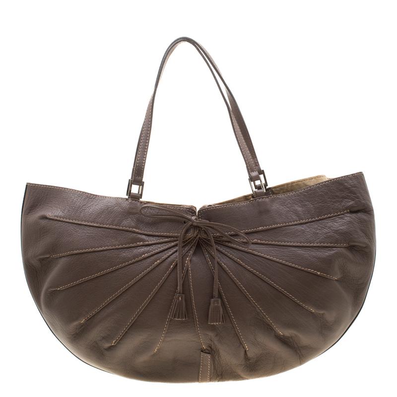 This hobo by Anya Hindmarch arrives in a unique shape and design. It is crafted from leather and detailed with a bow tassel on the front. The bag is equipped with two handles and a spacious suede interior where you can stow all your