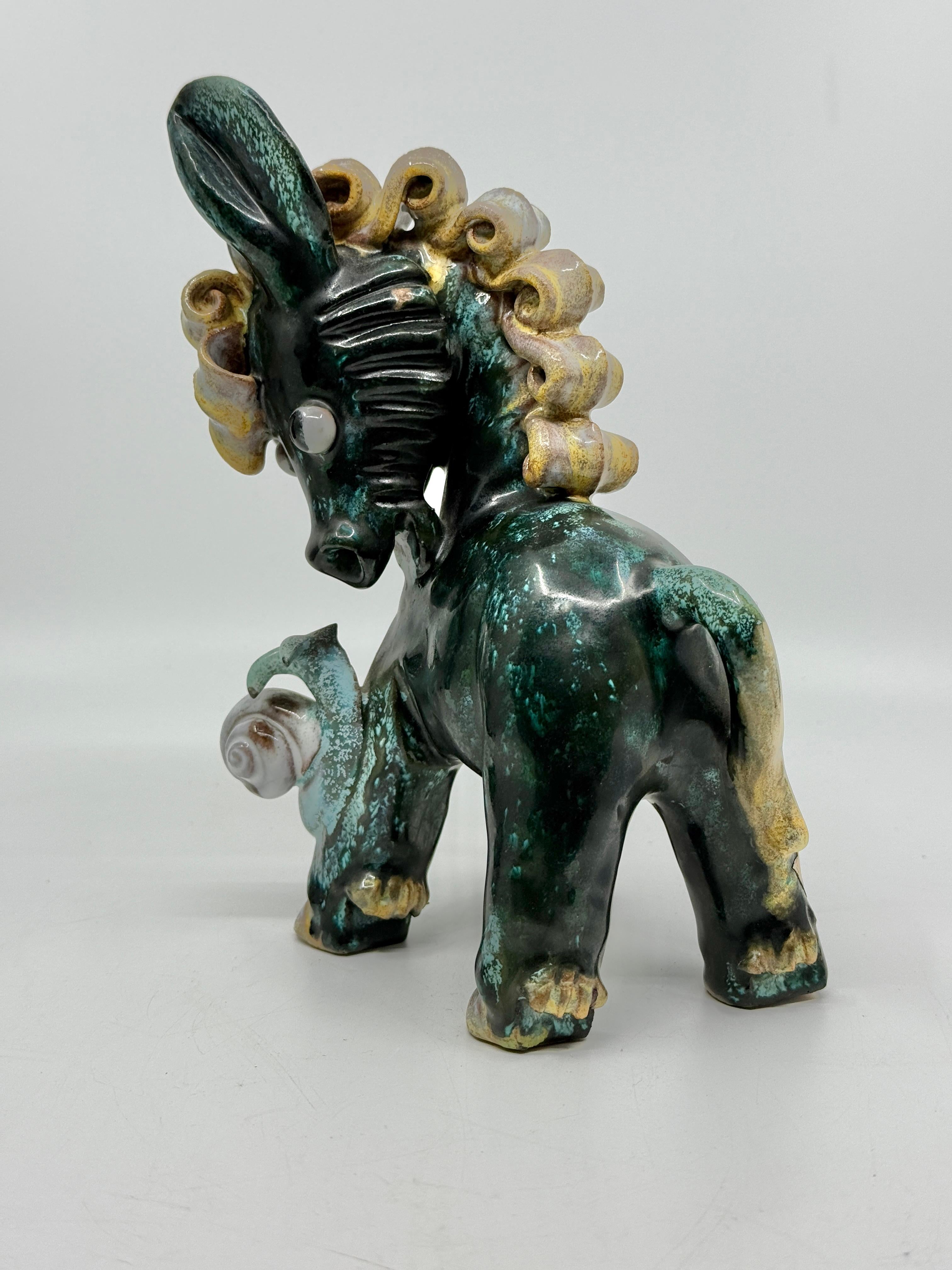 a cute whimsical Donkey with a snail made by Anzengruber Keramik and retailed by Rasper and Sohne of Vienna. This lovely little piece retains its original Anzengruber foil label as well as the original foil label of the retailer on the bottom. 
In