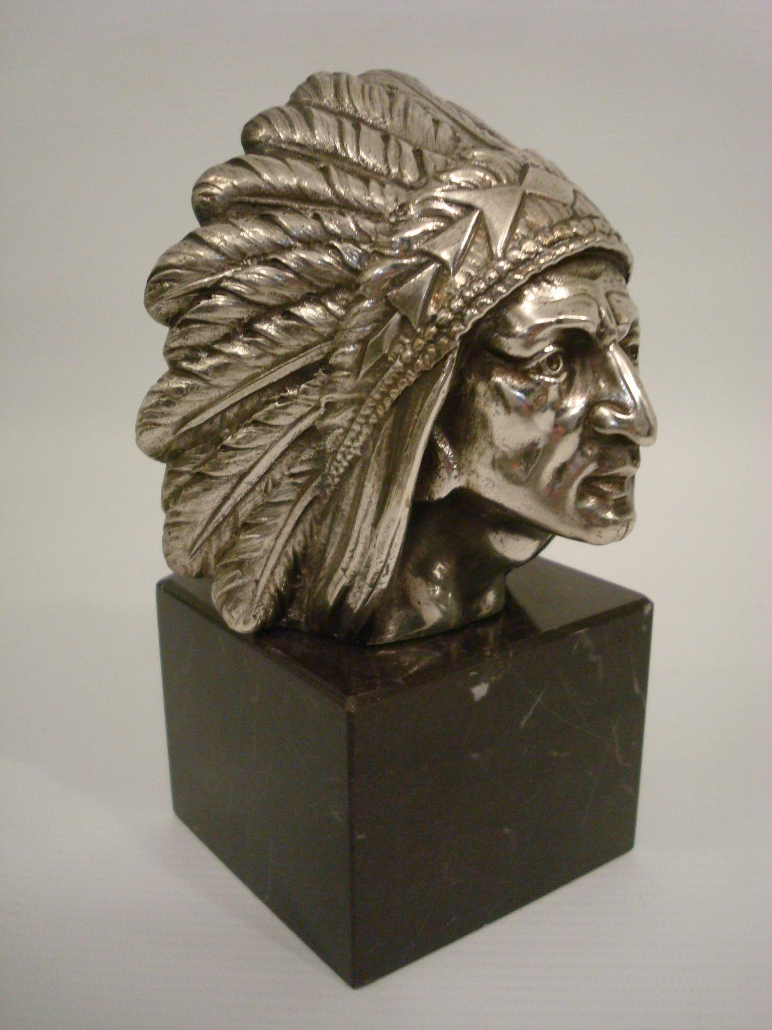 Tête de chef indien Apache Mascotte de voiture - Décoration de capot / Presse-papiers.
Conçu par l'éditeur H. Briand, Paris. Bronze argenté. Monté sur une base en marbre noir. Il possède un trou à l'arrière de la tête, ce qui permet de l'utiliser