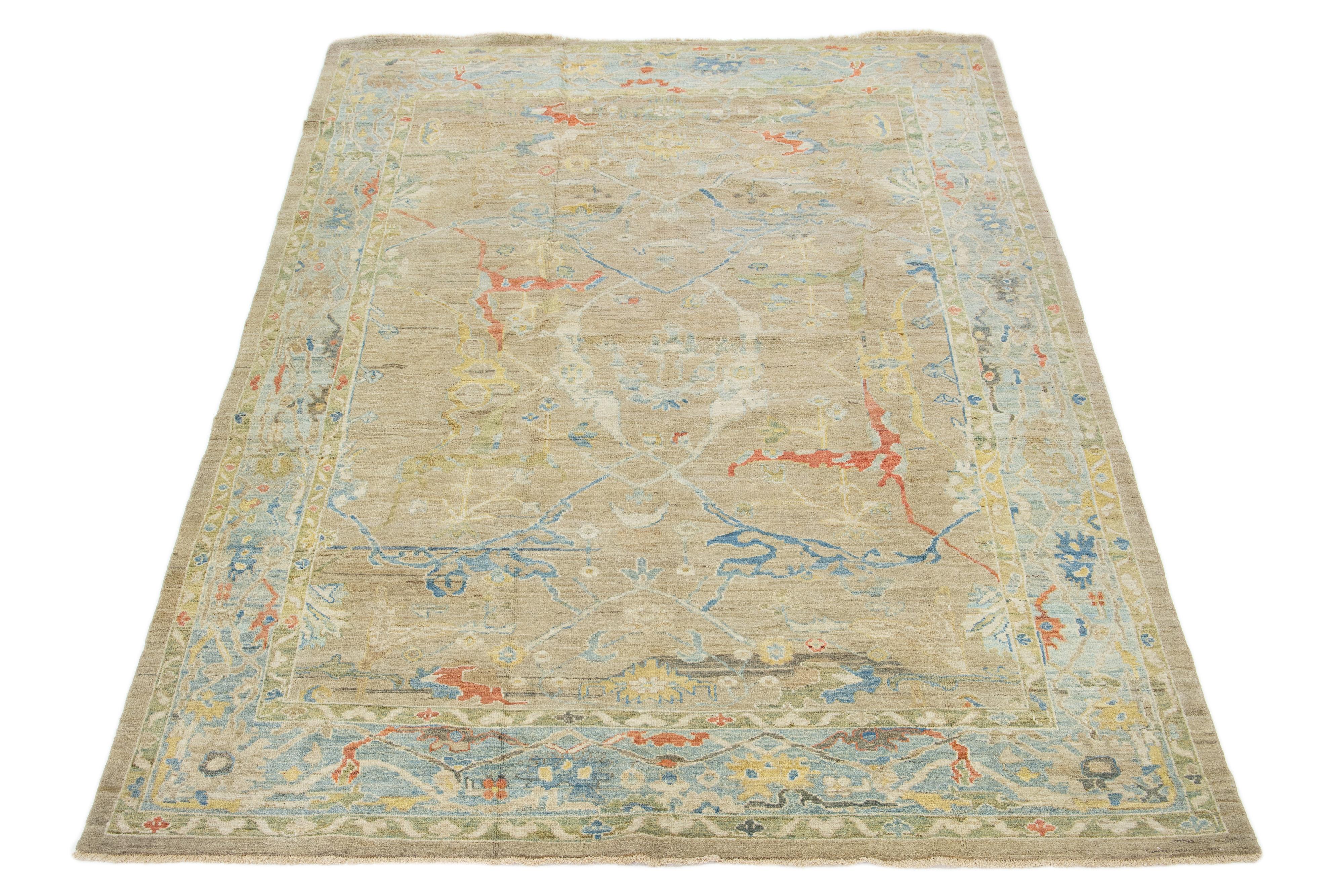 Questo tappeto in lana annodato a mano ha uno sfondo marrone chiaro e una cornice blu ornata da disegni multicolore all-over.

Questo tappeto misura 8'2'' x 12'1''.