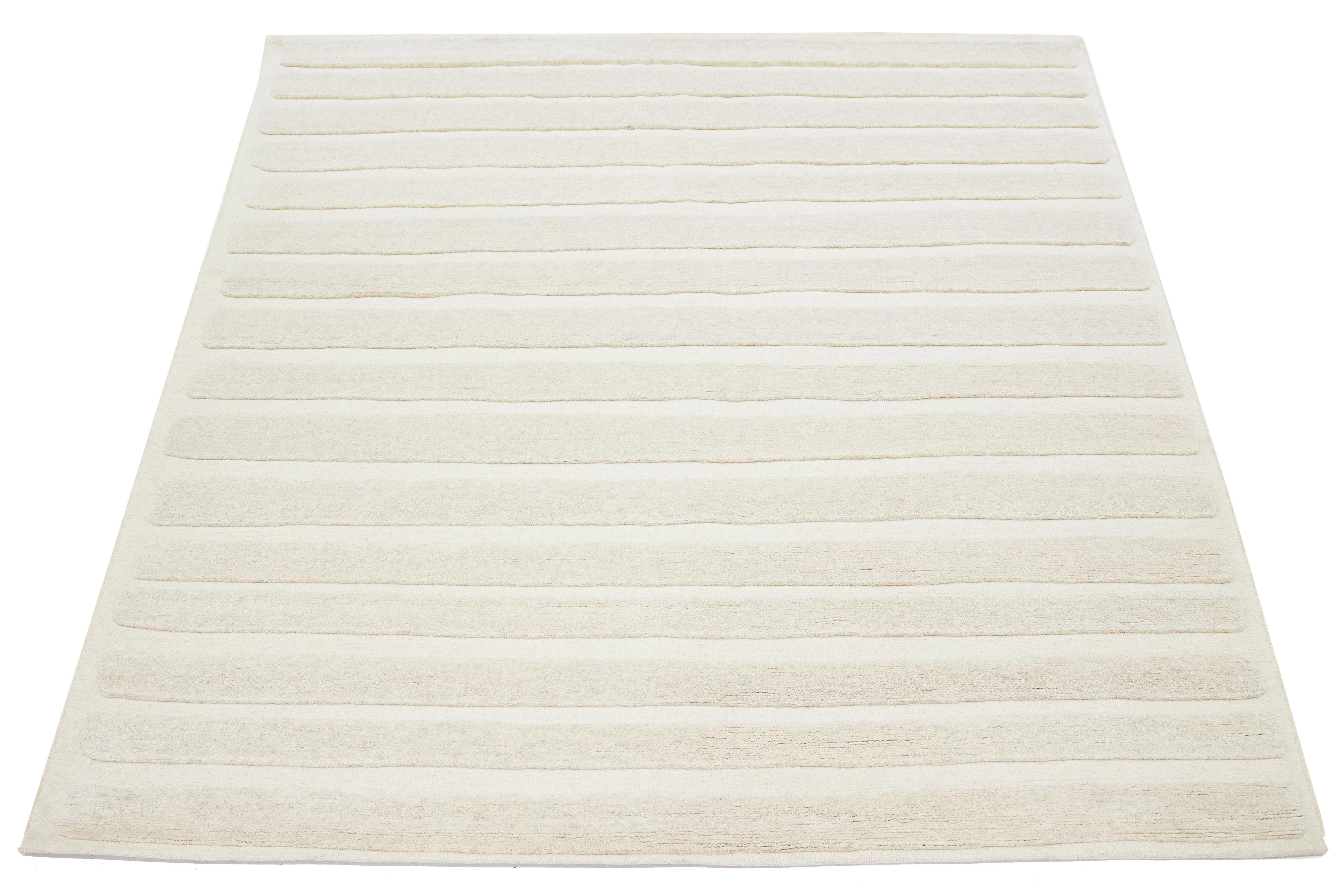 This hand-knotted rug in a Moroccan style is made of wool and features a mesmerizing minimalist aesthetic. It is designed with contemporary stripes on a natural ivory background.

This rug measures 8'2