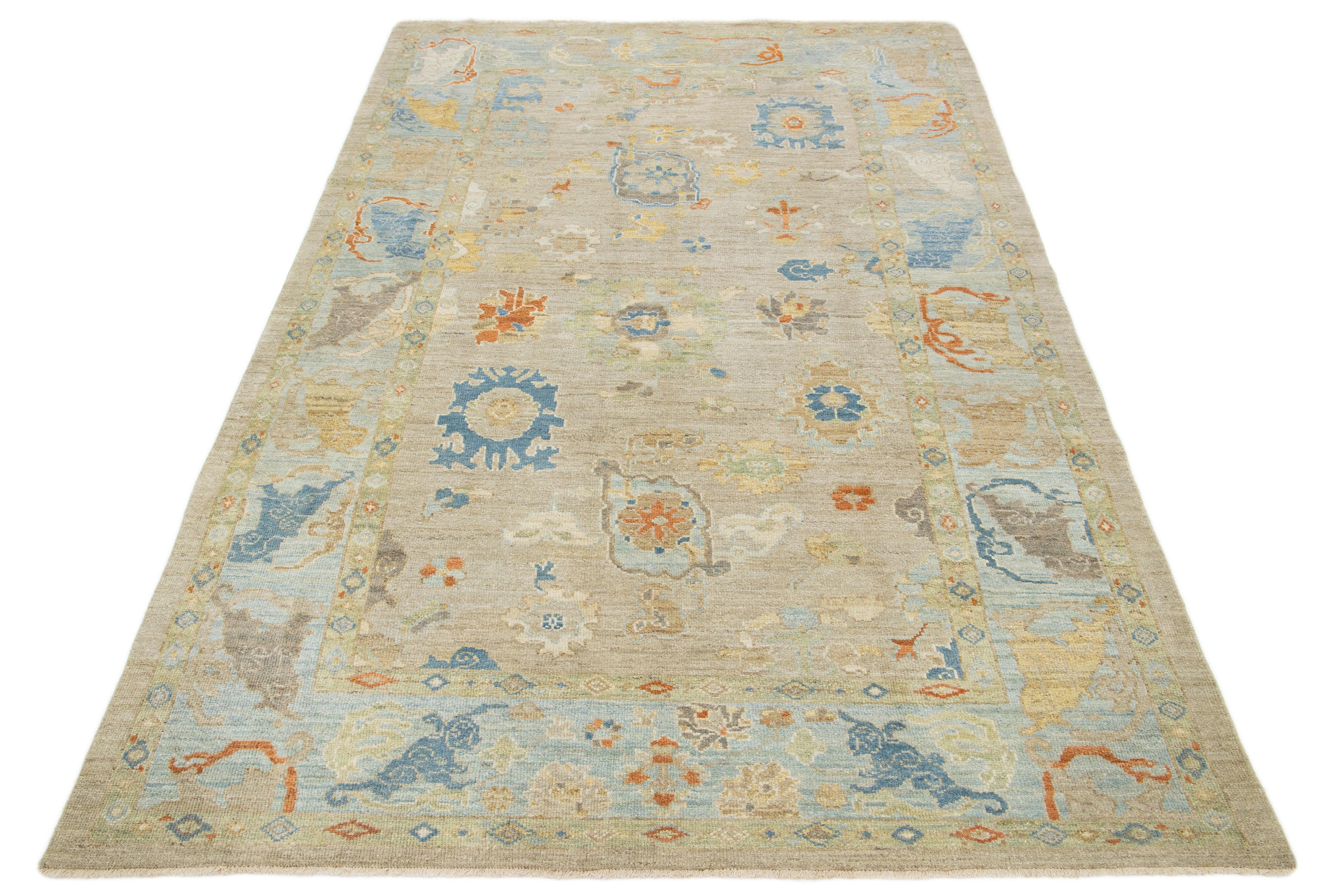 Questo tappeto in lana annodato a mano ha uno sfondo marrone chiaro e una cornice blu ornata da disegni multicolore all-over.

Questo tappeto misura 6'2'' x 10'2''.