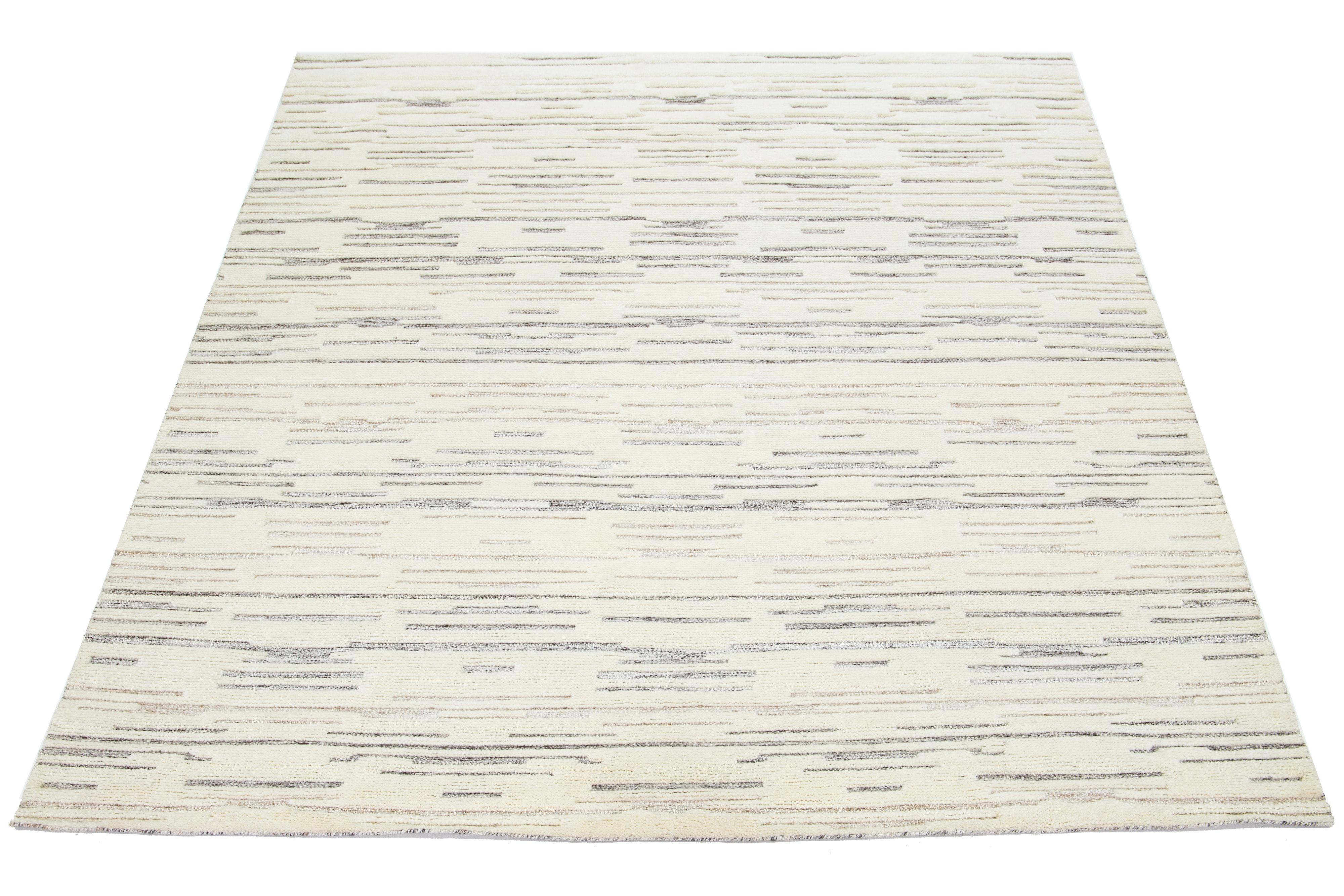 This hand-knotted Moroccan-style wool rug features a beautiful modern design with a natural ivory background. It showcases a stunning striped pattern in gray and brown.

This rug measures 8' x 10'.