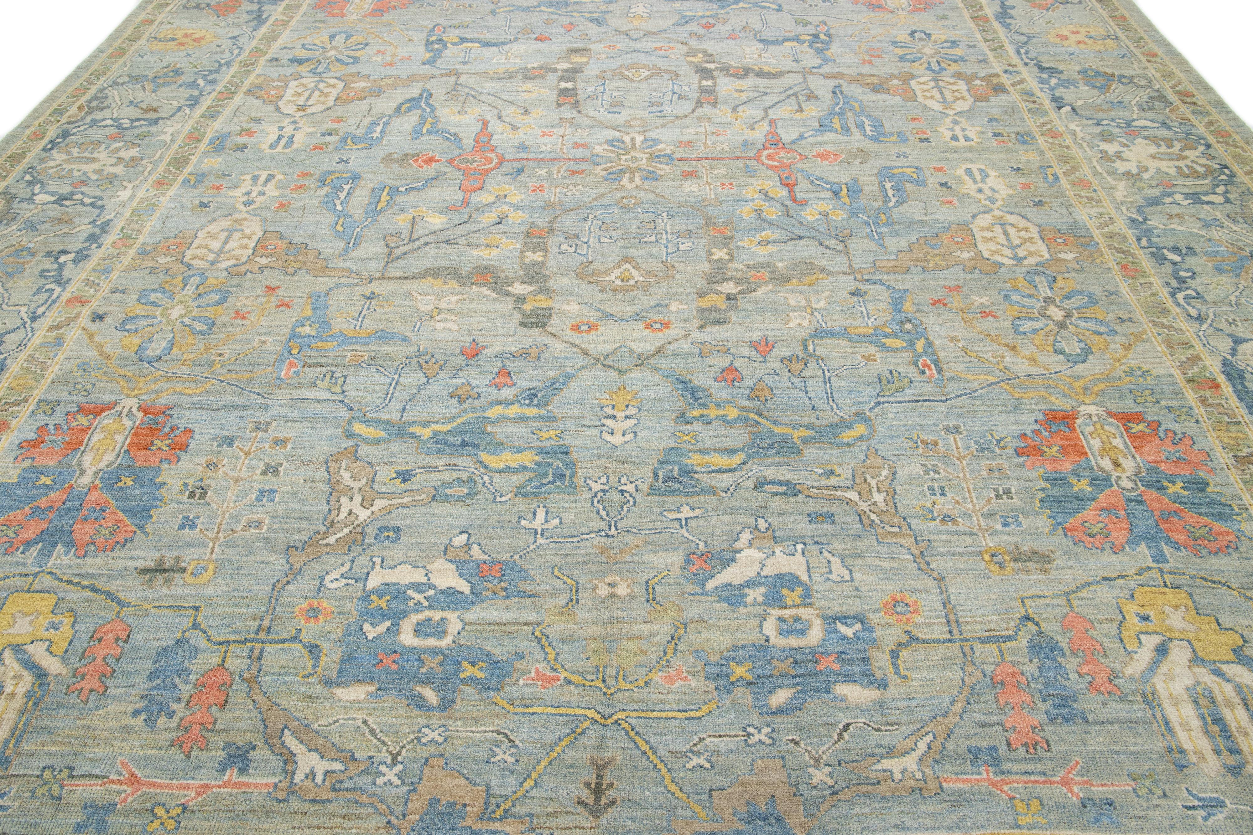Ce tapis en laine noué à la main présente un fond bleu clair orné de motifs multicolores all-over.

Ce tapis mesure 11'8'' x 15'1''.
