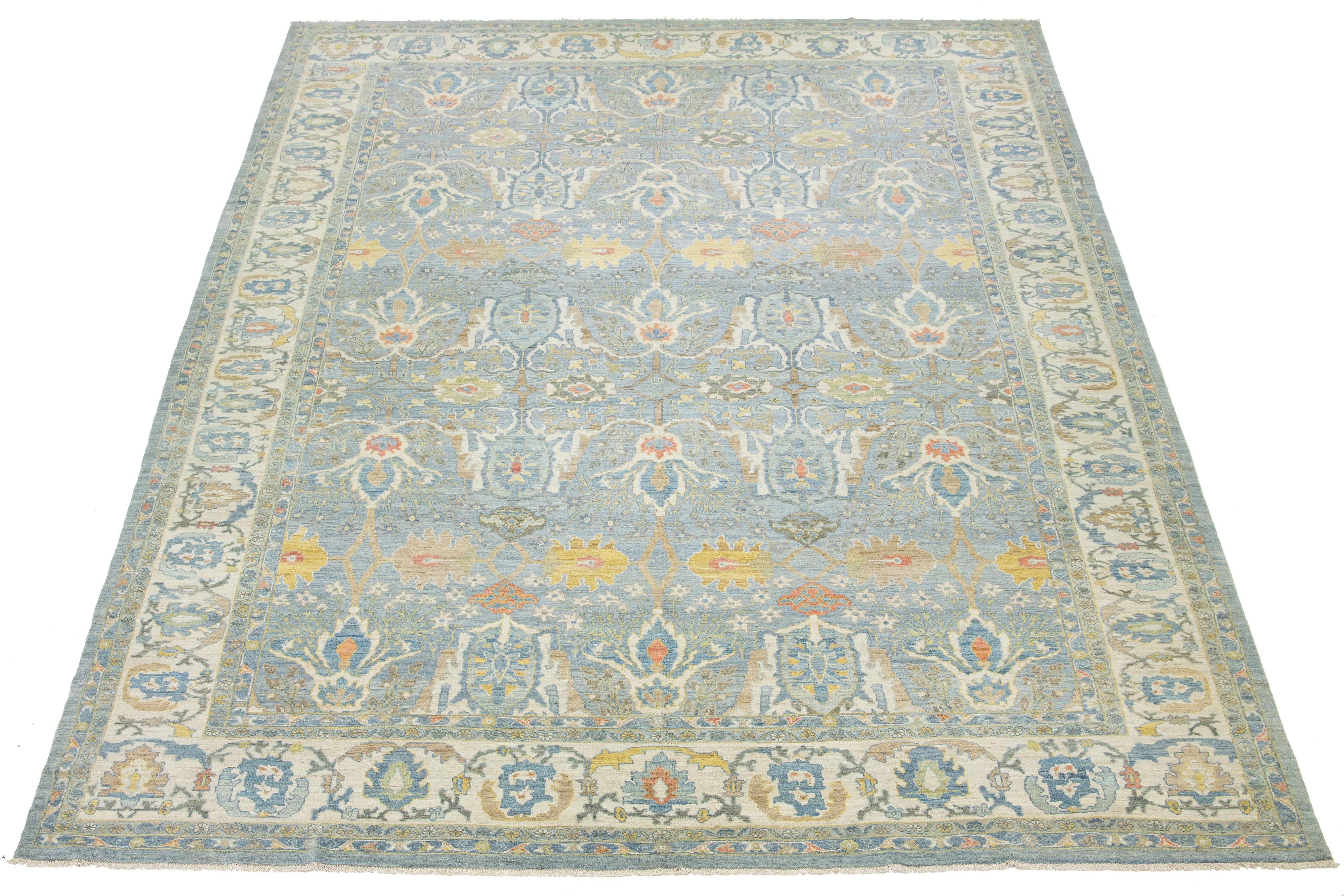 This beautifully crafted hand-knotted oversized Sultanabad wool rug showcases a soothing light blue background embellished with lively, multicolored designs. It enhances your space and makes a compelling statement about artistic craftsmanship and