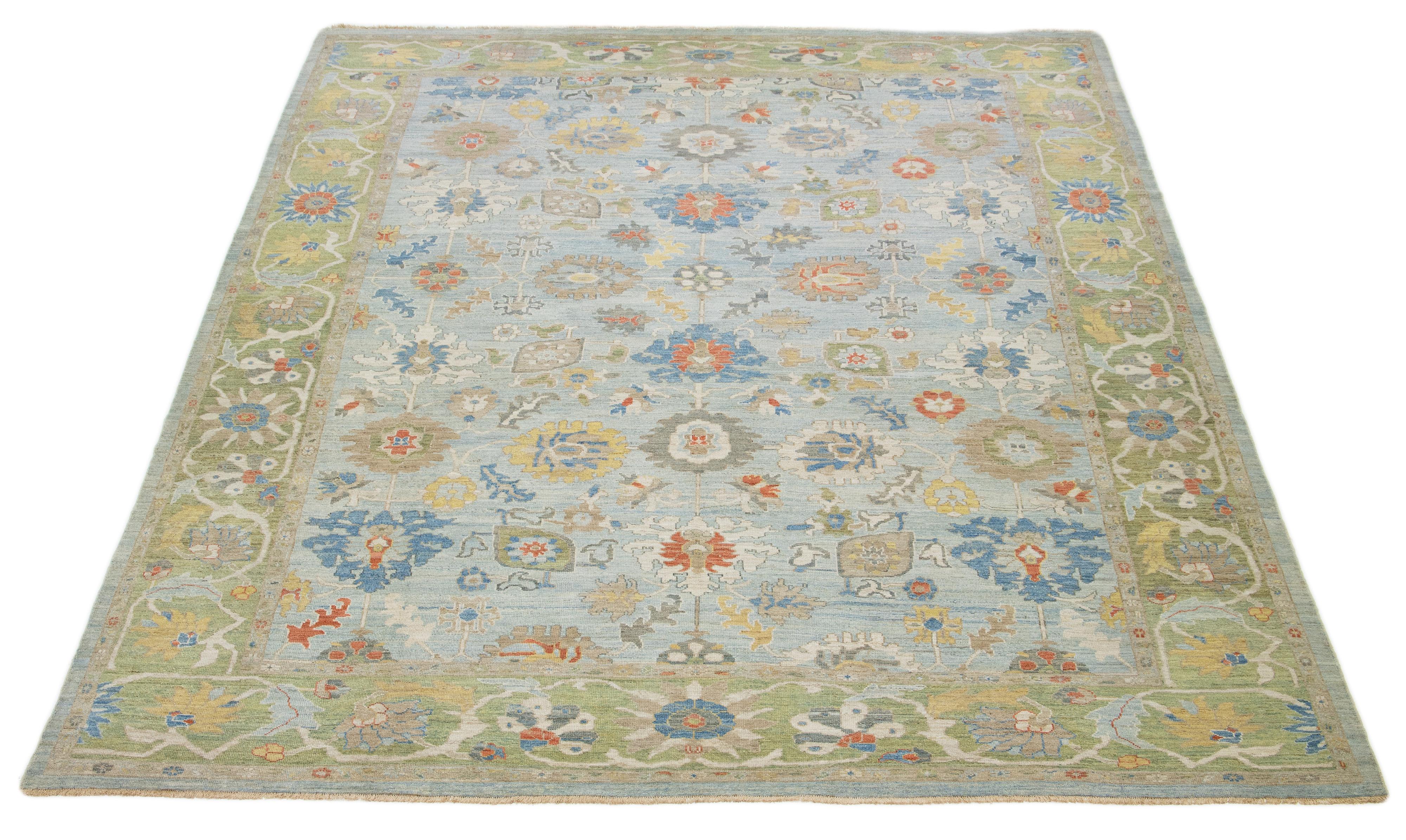 Dieser handgeknüpfte Wollteppich hat einen hellblauen Hintergrund mit grüner Bordüre und mehrfarbigen Allover-Motiven.

Dieser Teppich misst 12'7'' x 15'6''.