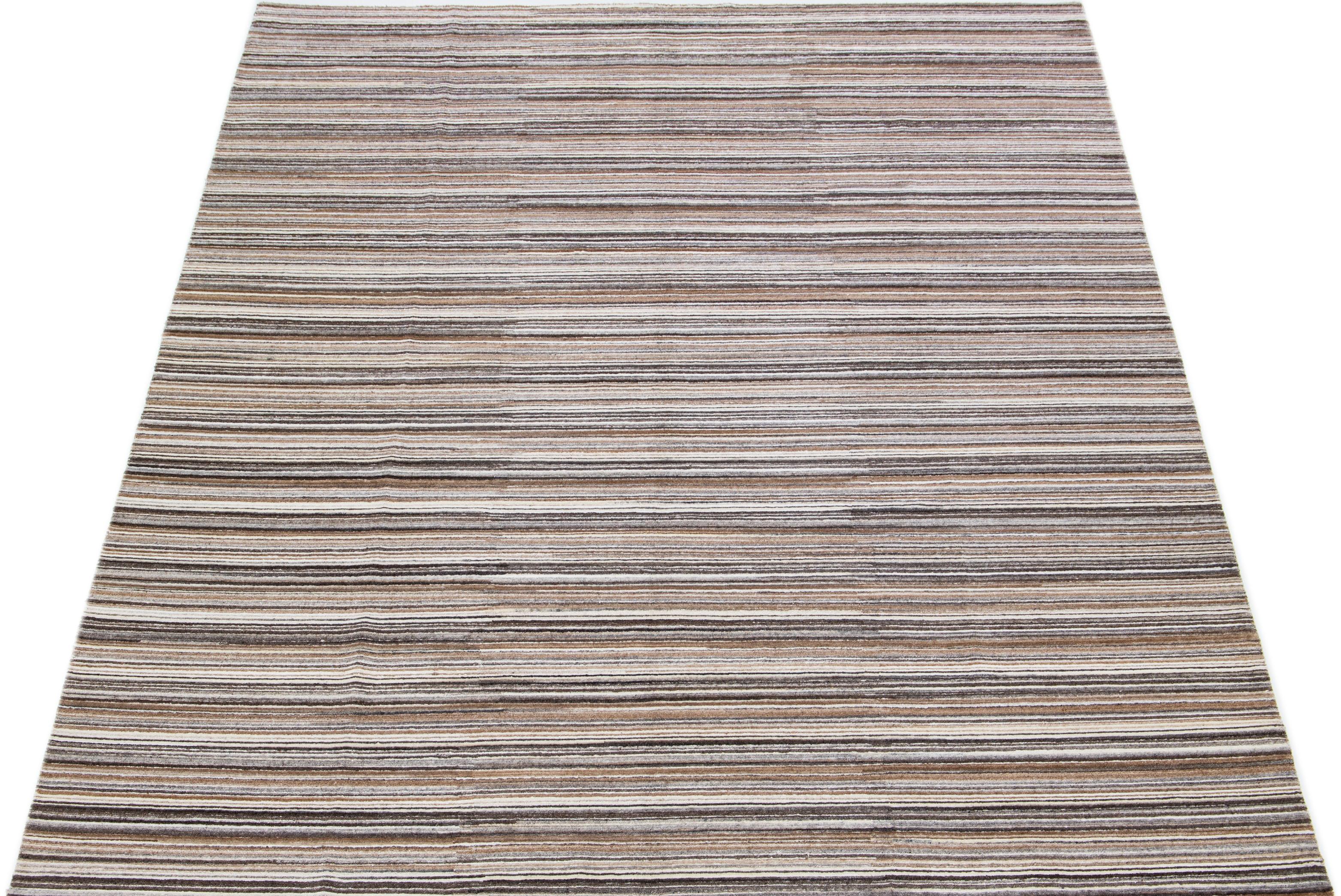 This contemporary handmade bamboo & silk Indian groove rug boasts a striped field. It is enriched with gray, ivory, and brown accents, all contributing to a stylish all-over design that perfectly embodies the essence of 21st-century
