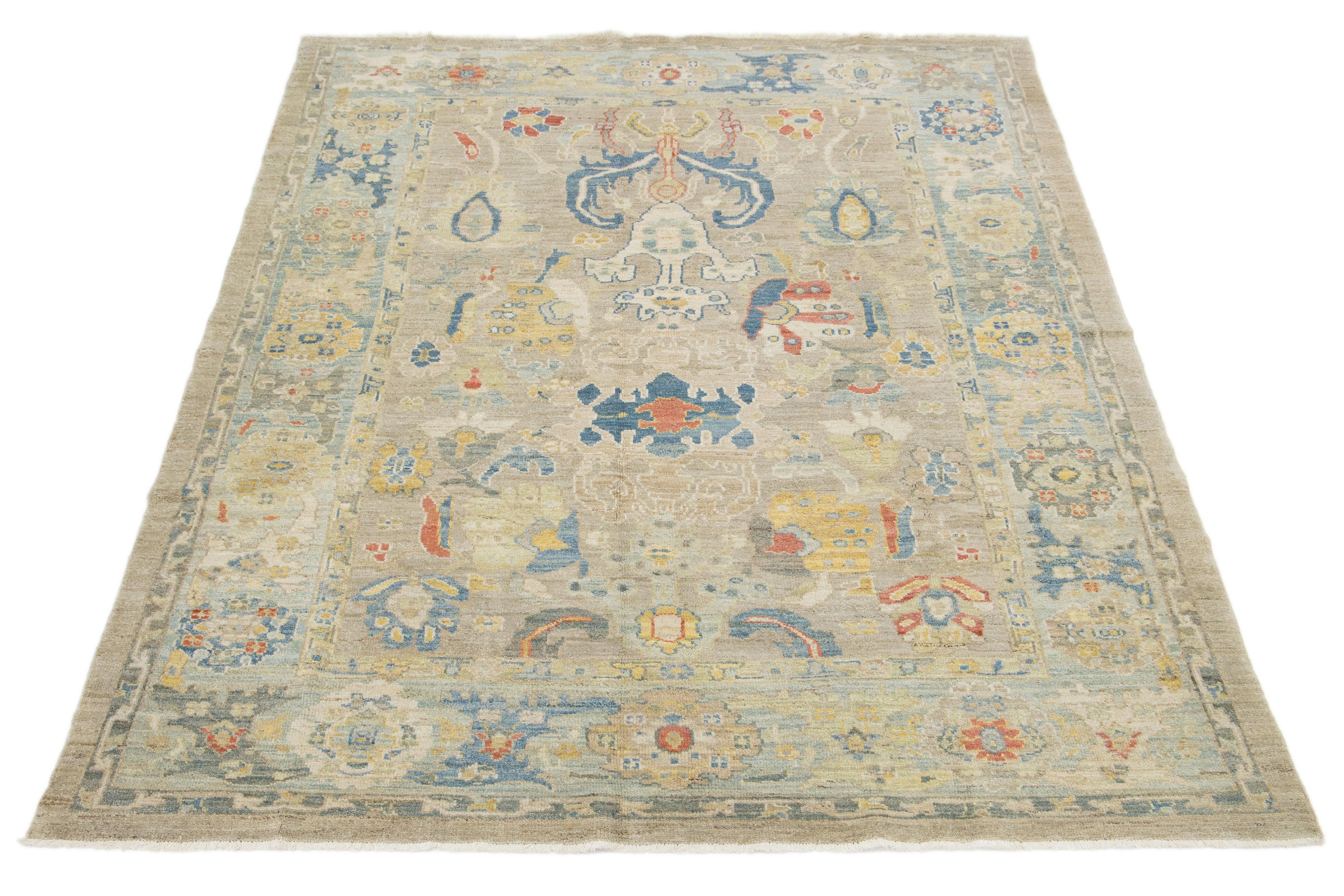 Dieser handgeknüpfte Wollteppich hat einen beigen Hintergrund mit einem blauen Rahmen, der mit mehrfarbigen Akzenten in einem Allover-Muster verziert ist.

Dieser Teppich misst 6'10'' x 9'5