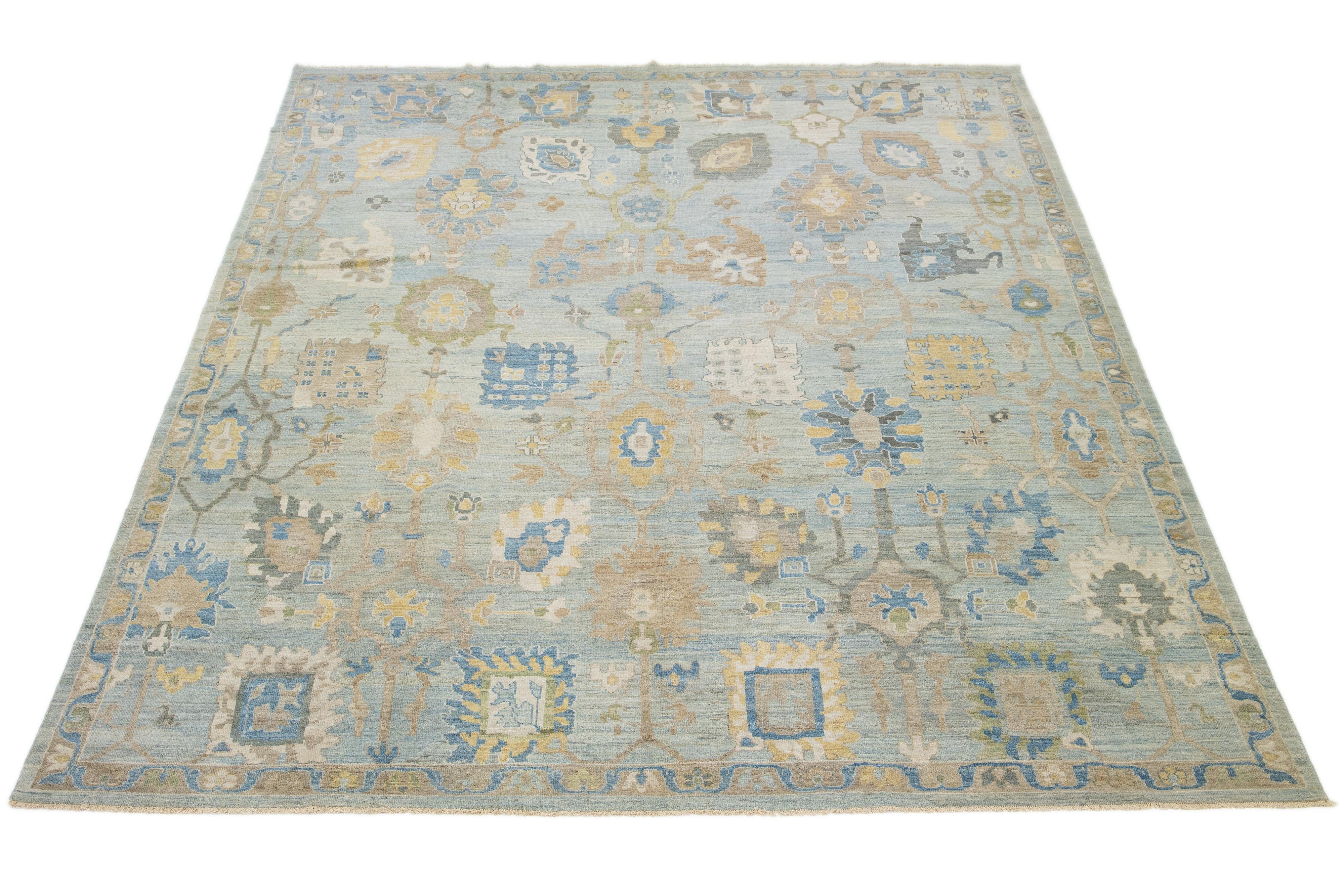Dieser handgeknüpfte Wollteppich hat einen hellblauen Hintergrund, der mit braunen und gelben Akzenten in einem Allover-Muster verziert ist.

Dieser Teppich misst 12'2'' x 15'11''.