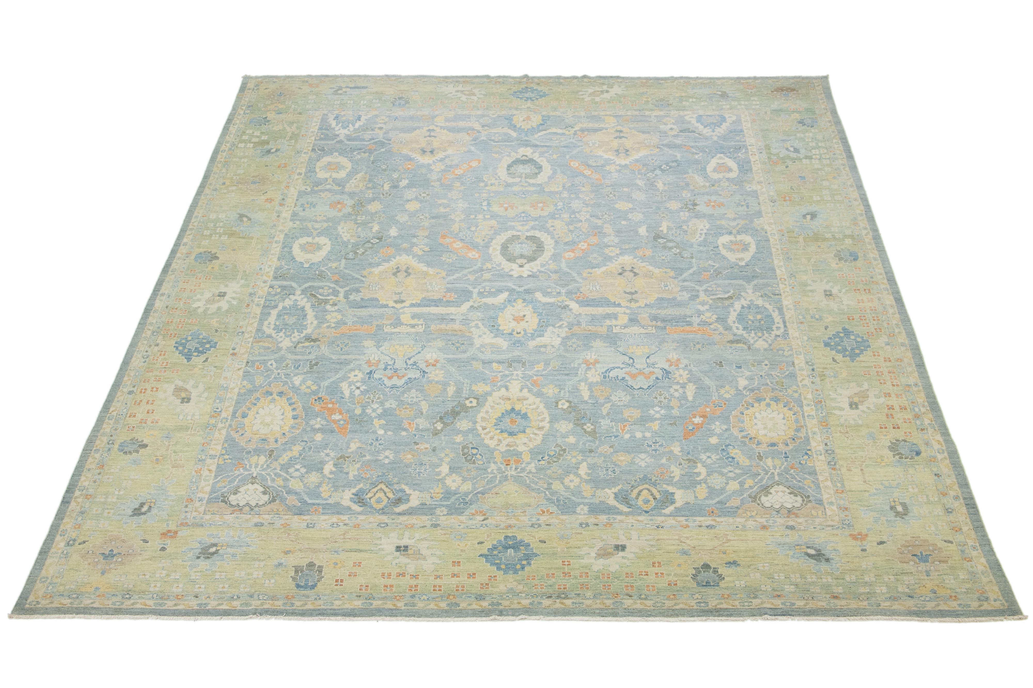 Experience the beauty of this stunning hand-knotted oversized Sultanabad wool rug, showcasing a serene light blue backdrop and a green border, beautifully complemented by an array of colorful patterns that embellish the entire rug. Elevate your