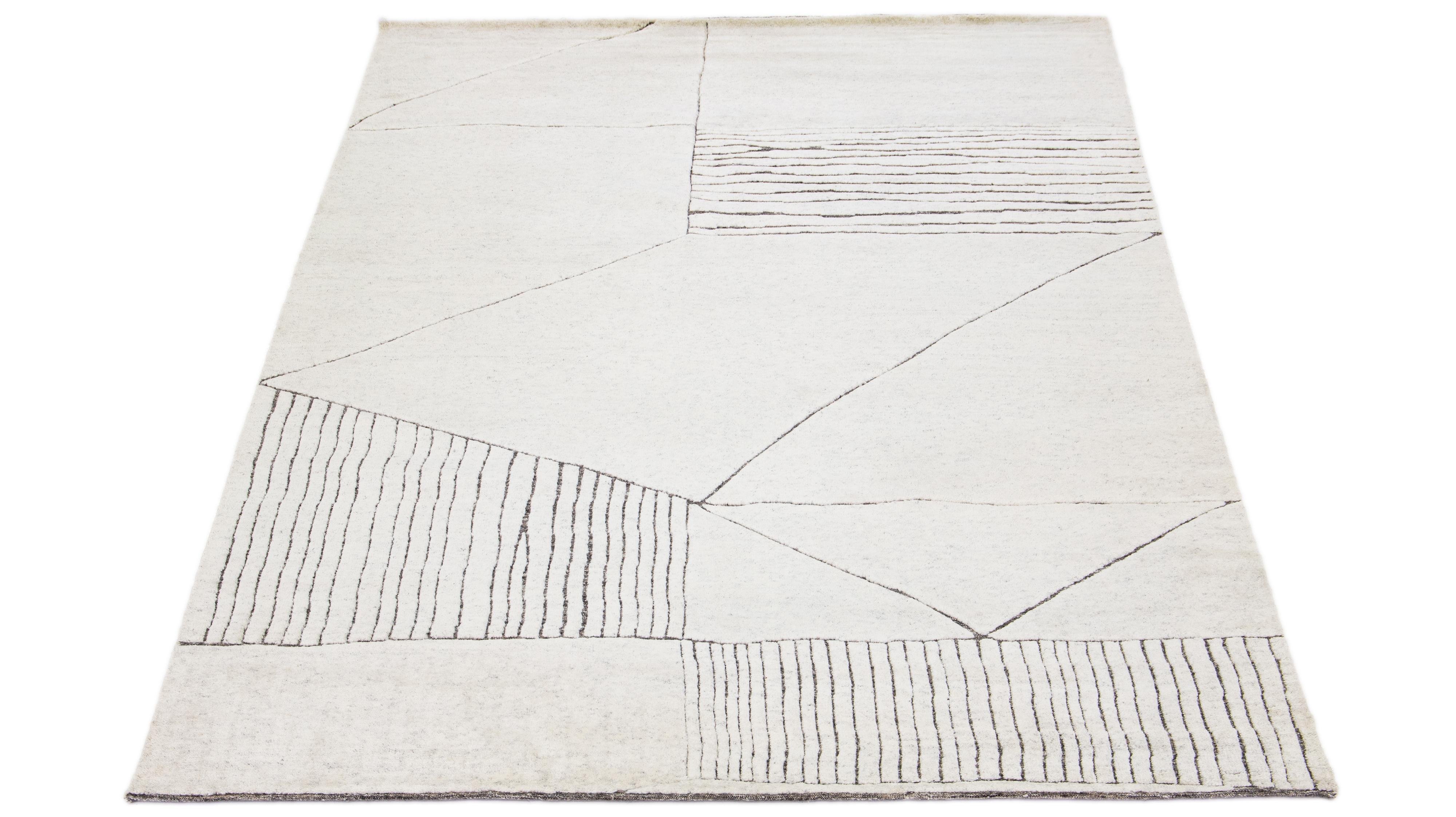 This luxurious wool rug features a timeless Moroccan pattern in a contemporary abstract Minimalist style, utilizing Ivory tones to create a sleek and modern look. It is crafted using traditional hand-knotting techniques, ensuring exceptional quality