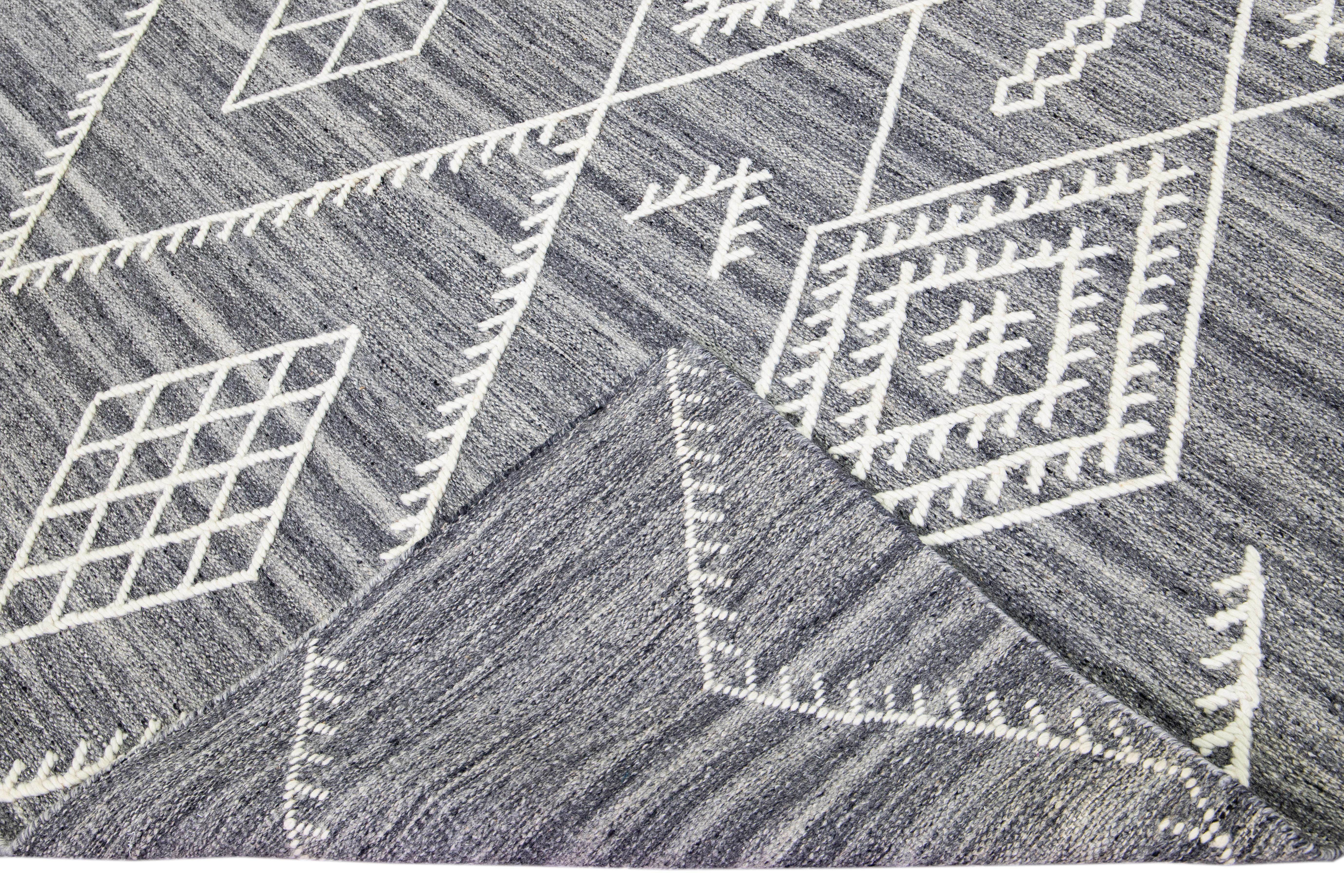 Beautiful kilim handmade wool rug with a gray field. This custom modern flatweave rug part of our Nantucket collection has ivory accents and features a gorgeous all-over geometric coastal design.

This rug measures: 9' x 12'.

Our rugs are