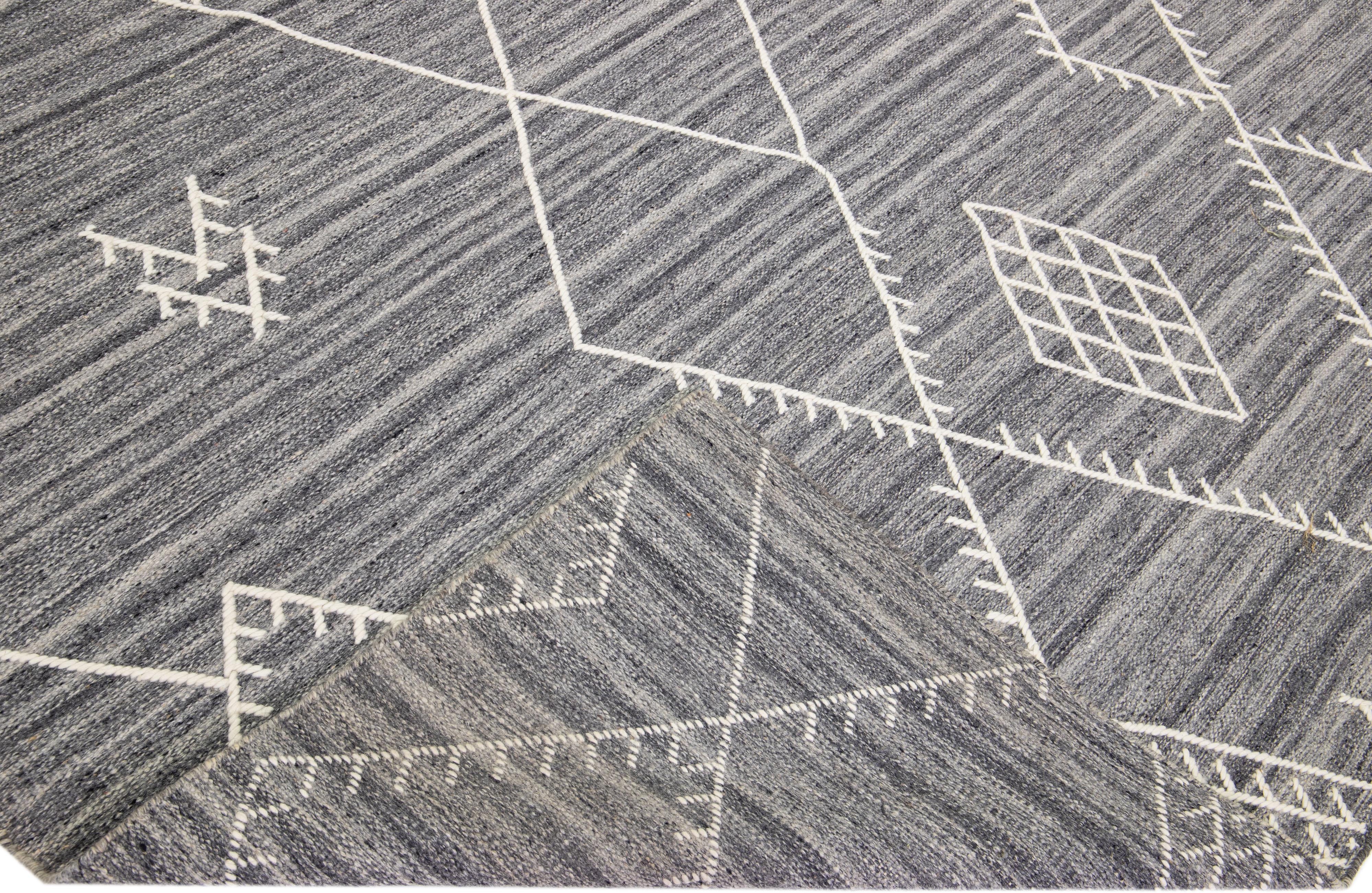 Schöner handgefertigter Kelimteppich aus Wolle mit grauem Feld. Dieser moderne Flachgewebe-Teppich aus unserer Nantucket-Kollektion hat weiße Akzente und ein wunderschönes, geometrisches Küstendesign.

Dieser Teppich misst: 10'2