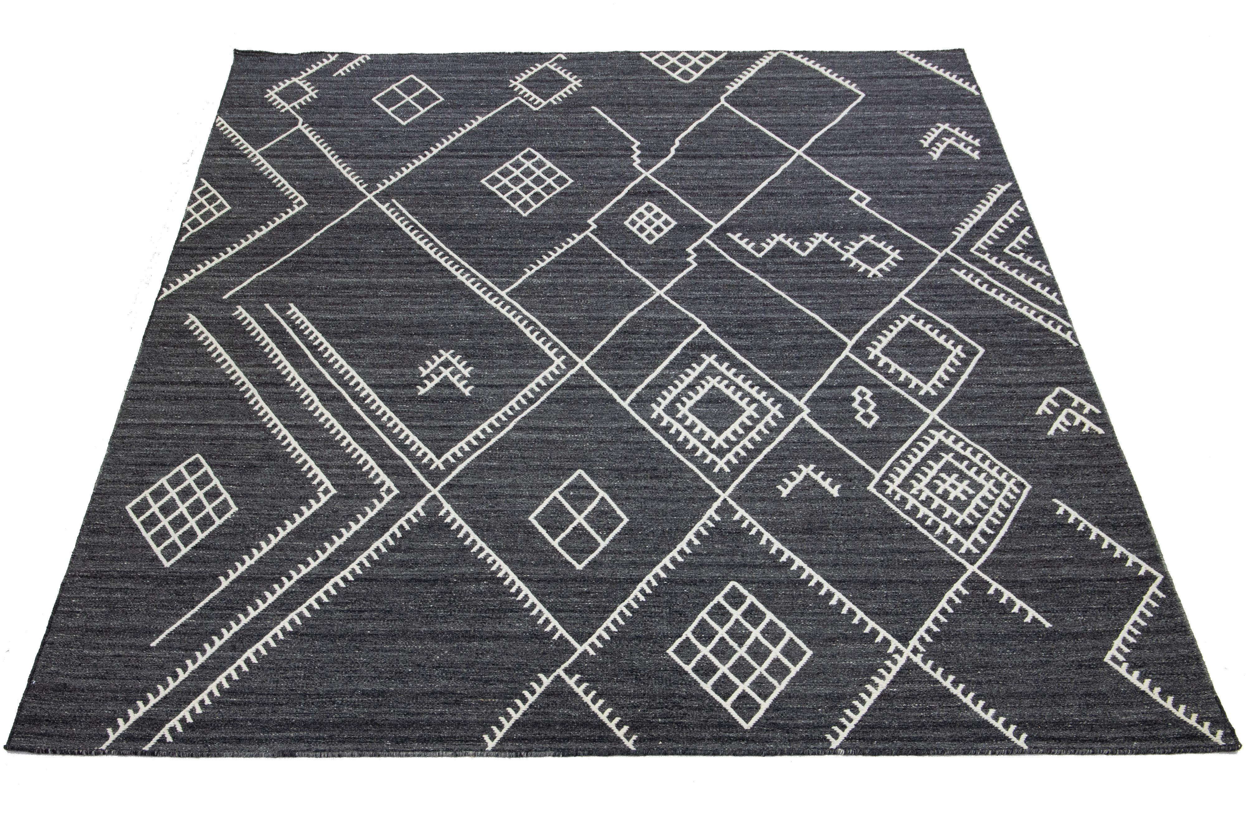 Si tratta di un bellissimo tappeto kilim in lana fatto a mano con un campo grigio antracite. Questo tappeto moderno e personalizzato a trama piatta della nostra collezione Nantucket presenta accenti avorio e uno splendido disegno geometrico costiero