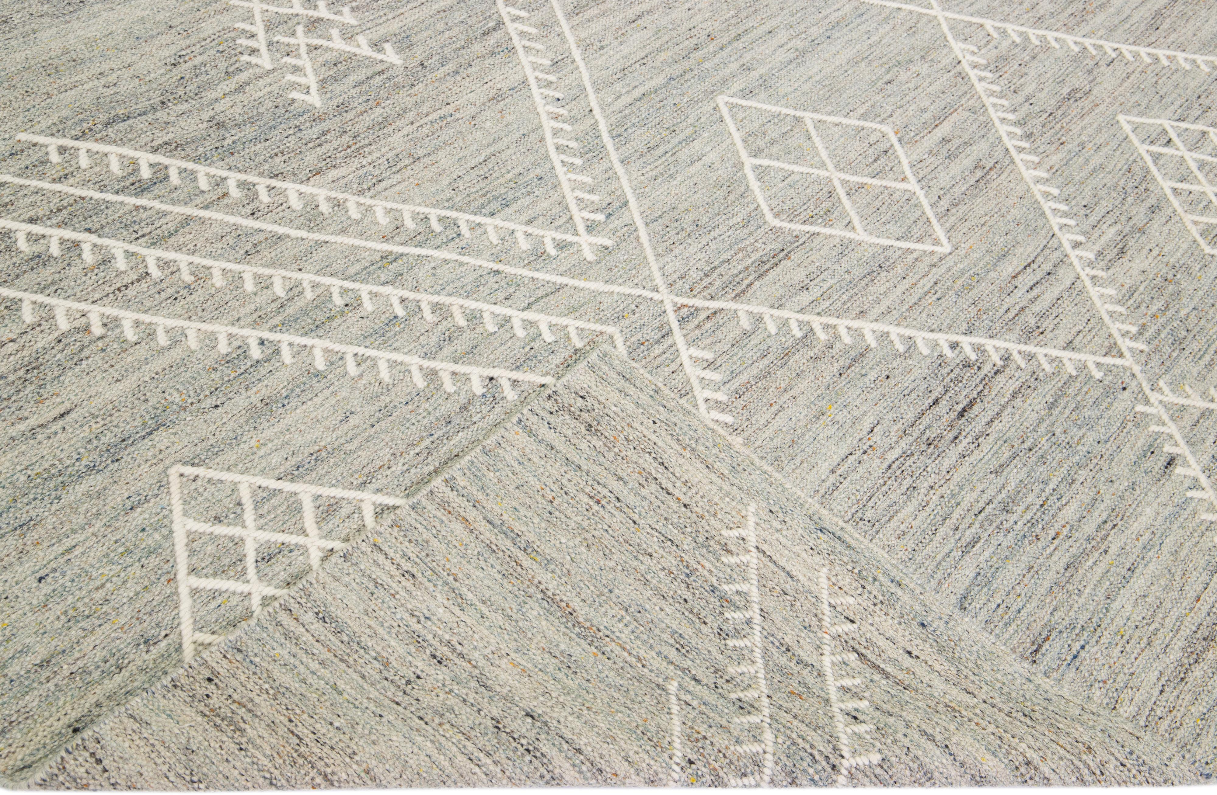 Beautiful kilim handmade wool rug with a gray field. This custom modern flatweave rug part of our Nantucket collection has ivory accents and features a gorgeous all-over geometric coastal design.

This rug measures: 12'2