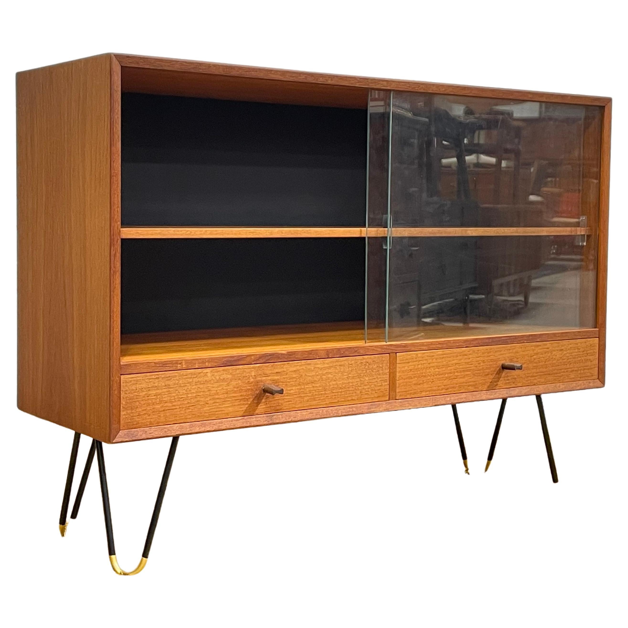 Apartment sized Walnut Mid-Century Modern BOOKCASE by Troeds, Made in Denmark. This super cute & solid piece has sliding glass doors, perfect for keeping the dust out. The legs are black and gold metal hairpin that are extremely sturdy. Two