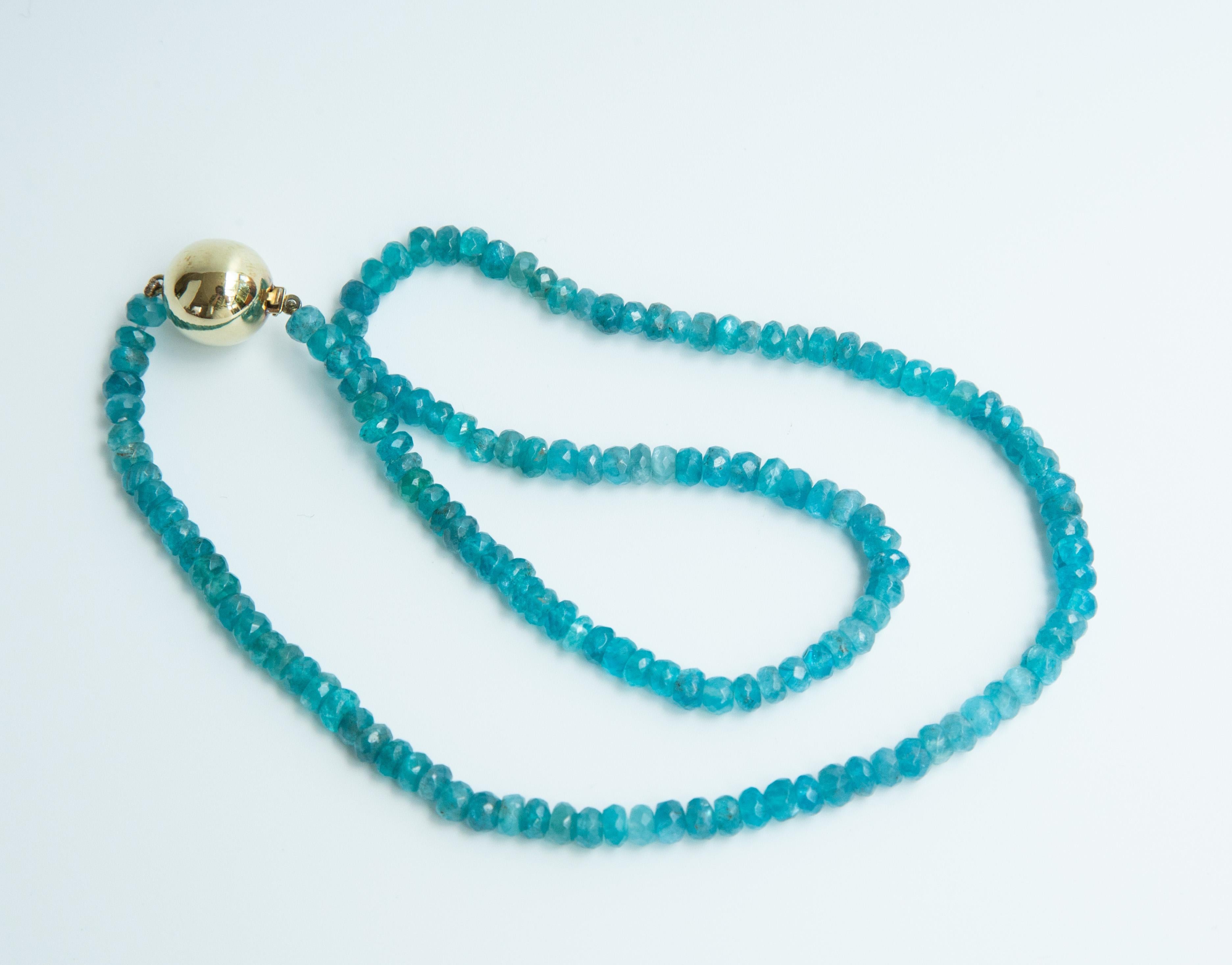 A vintage beaded necklace made of genuine faceted round apatite beads (5 mm) in vivid blue. The necklace features a 14 karat yellow gold ball lock (13 mm).  The weight of the necklace is 21.1 grams and the total length is 47 cm. The necklace is in