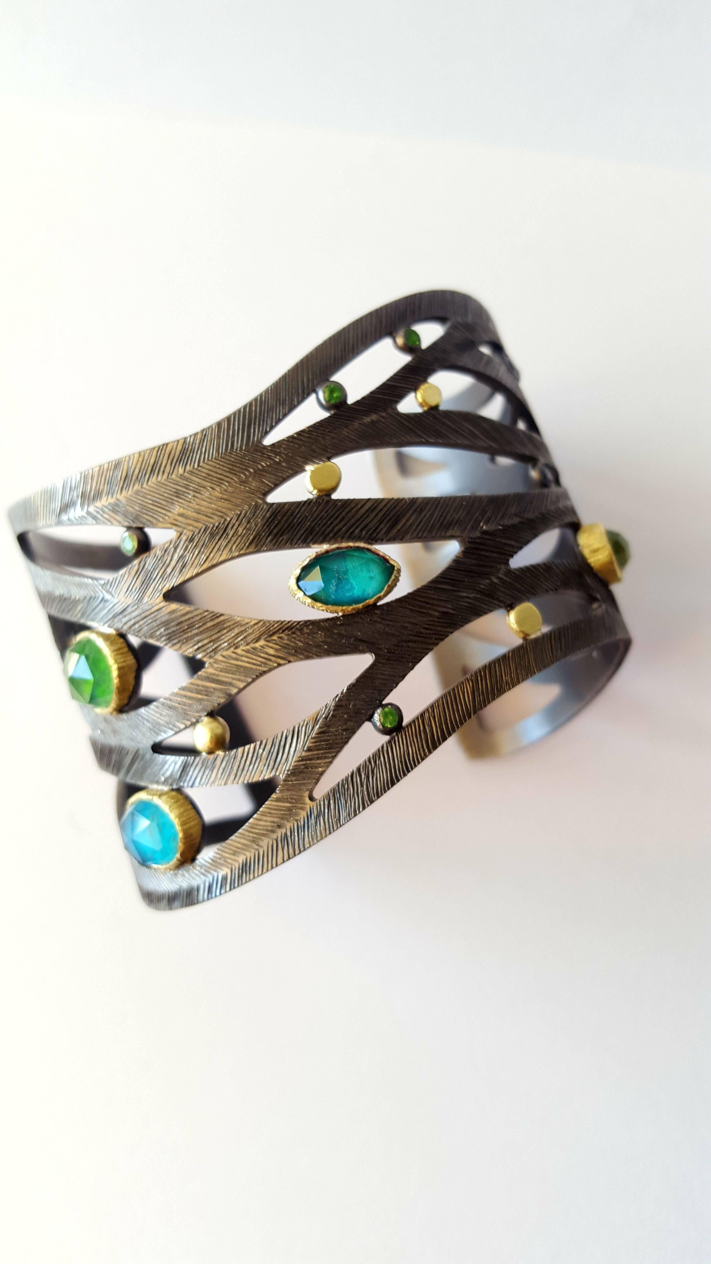 A stunning cuff bracelet in black rhodium plated sterling silver 925 and  18k green gold with apatite, dioptase, chrysocolla, tourmaline/rock crystal doublets and peridot. Very comfortable to wear this stunningly eye-catching bracelet has a very
