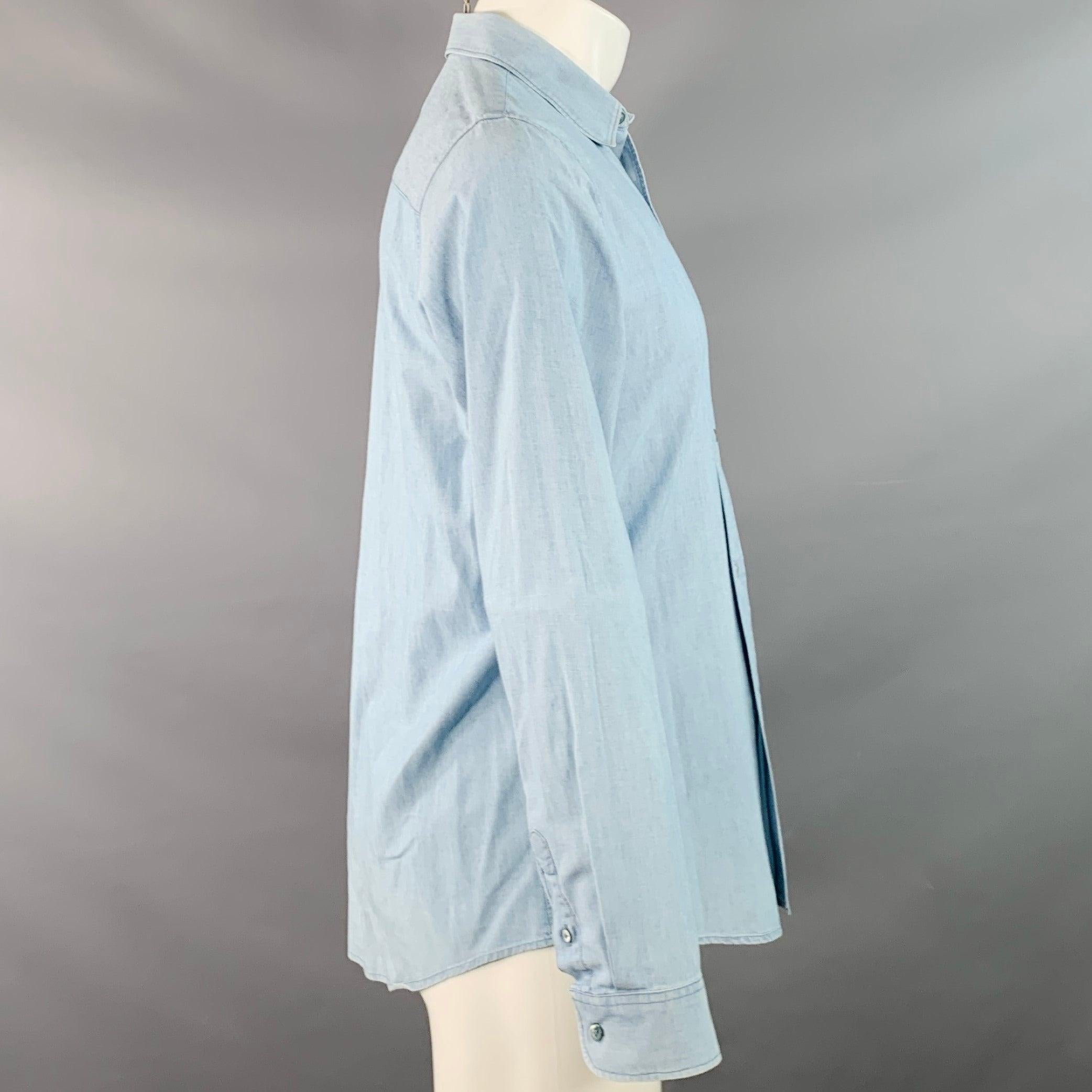 Chemise à manches longues A.P.C.
dans un chambray de coton bleu, avec un col ouvert, des poignets arrondis à un seul bouton et une fermeture à boutons. Excellent état d'origine.  

Marqué :   M 

Mesures : 
 
Épaule : 15.5 pouces Poitrine : 41